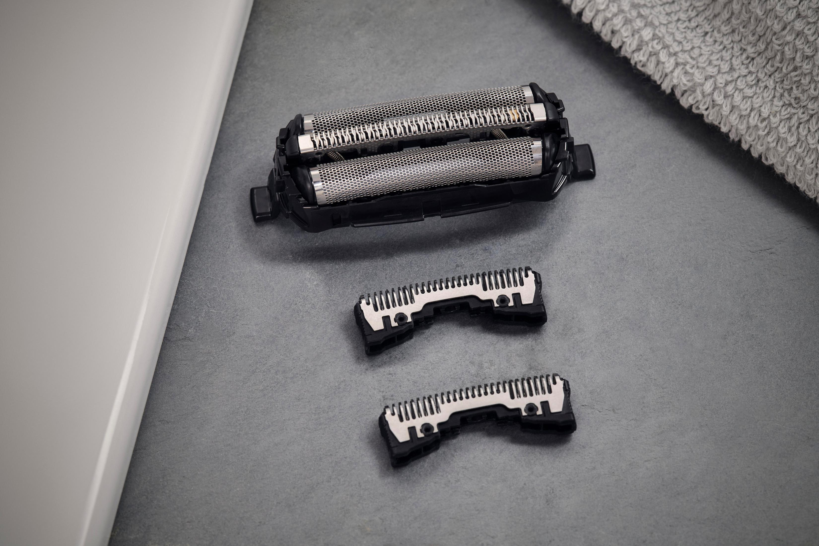 Ostrza i elementy golarki elektrycznej. Szare tło. Ręcznik leży z boku.