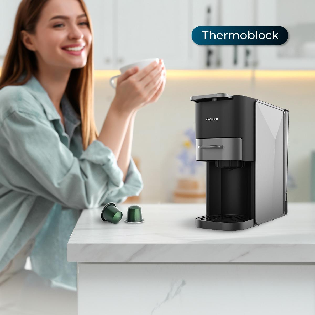 Czarny i szary ekspres do kawy stoi na białym blacie. Kobieta trzyma filiżankę w tle.