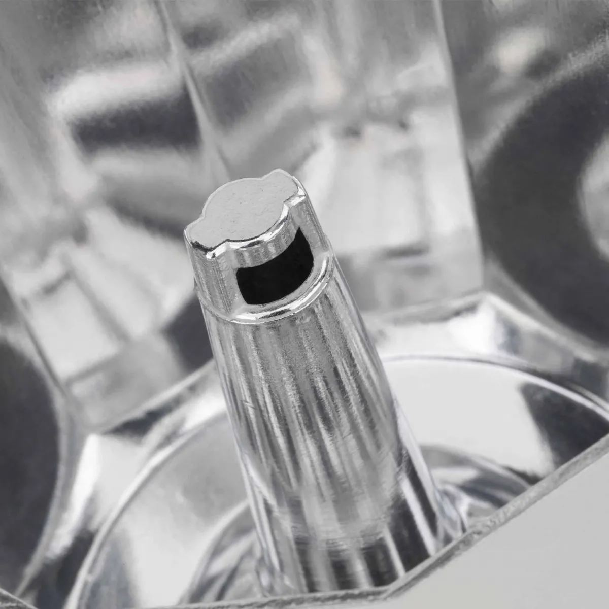 Zbliżenie wylewki srebrnego ekspresu do kawy, pokazujące wnętrze, błyszczące.