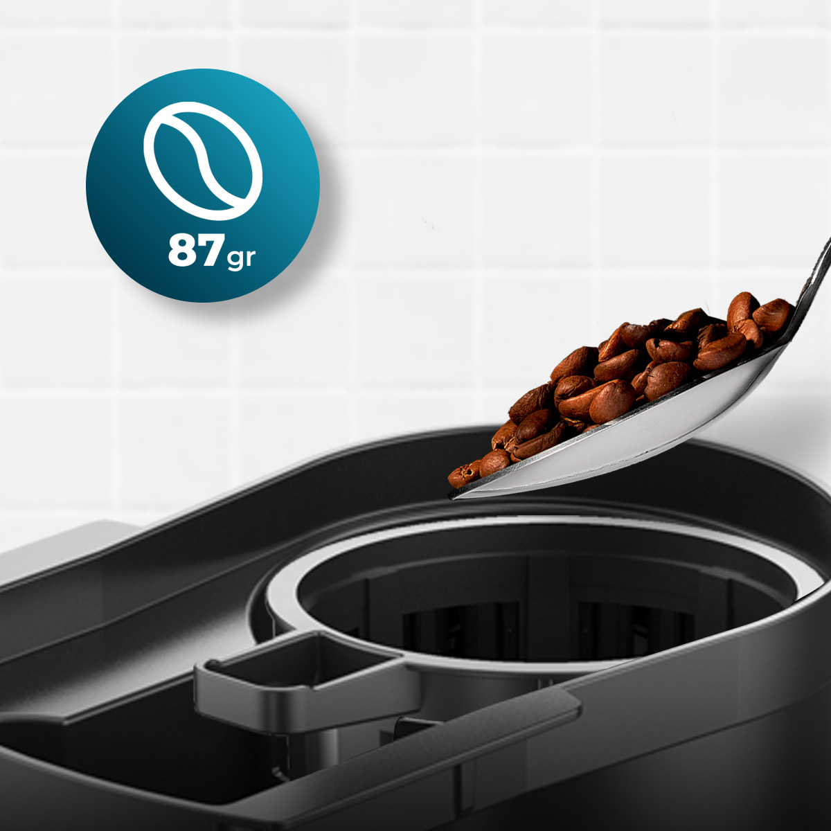 Łyżka ziaren kawy trzymana nad ekspresem do kawy. Widoczne niebieskie koło z napisem 87gr.
