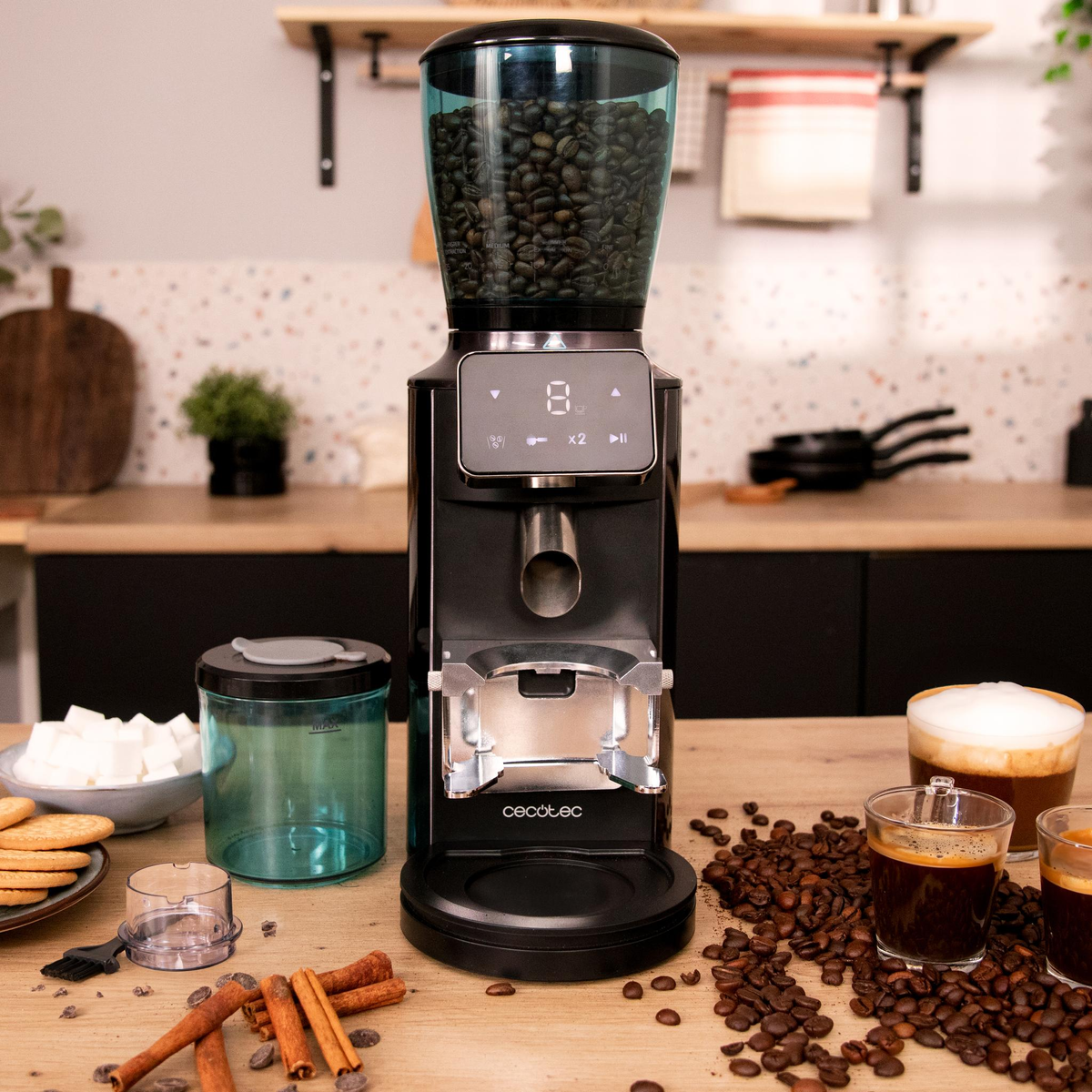 Un macinacaffè nero con un contenitore trasparente per i chicchi, circondato da chicchi di caffè e accessori.