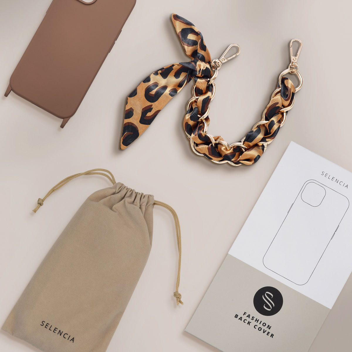 Vari accessori: custodia telefono, sciarpa, borsa e cover posteriore fashion. Tutto su superficie beige.