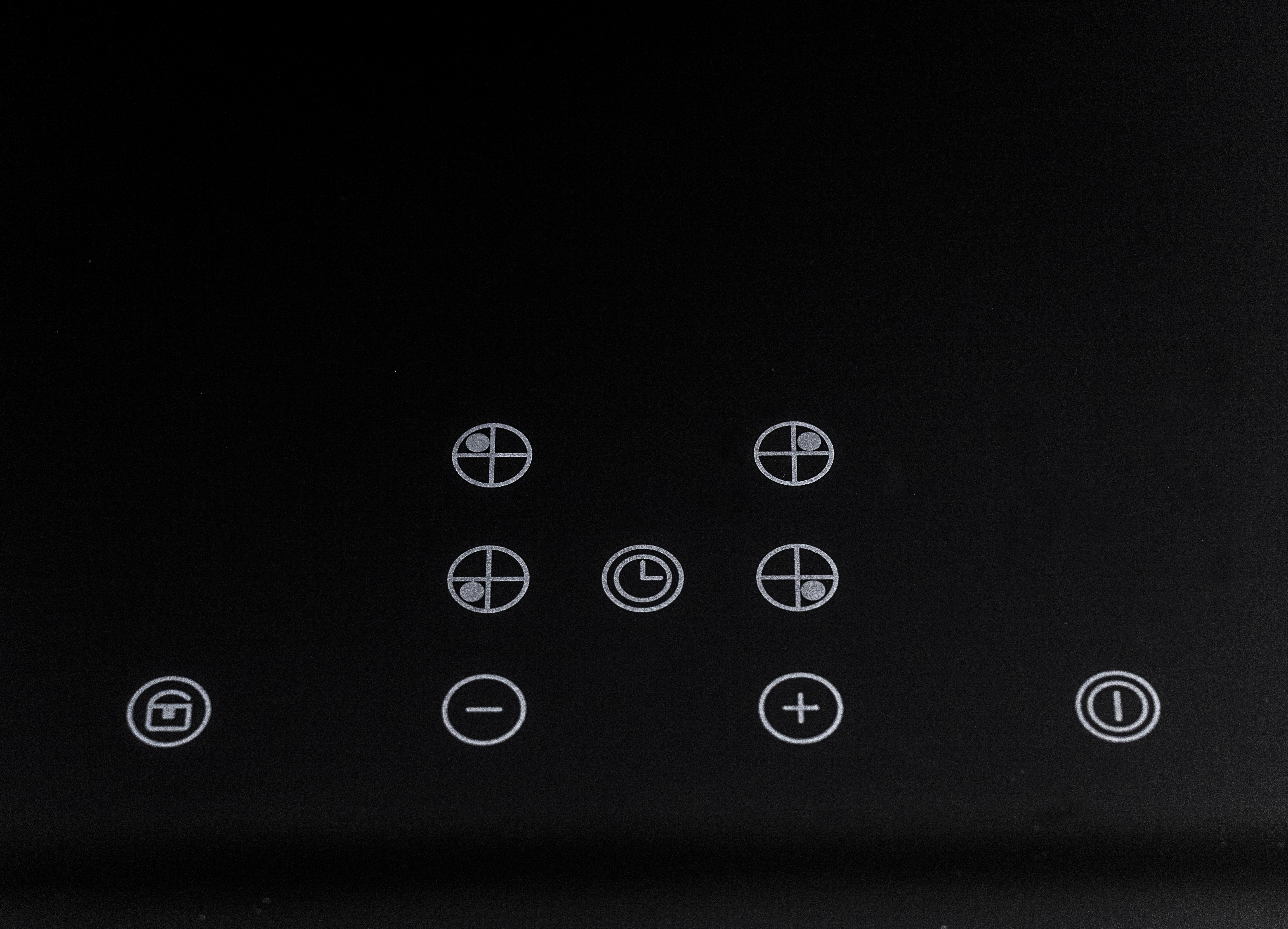 Black glass stove top with white icons for controls.