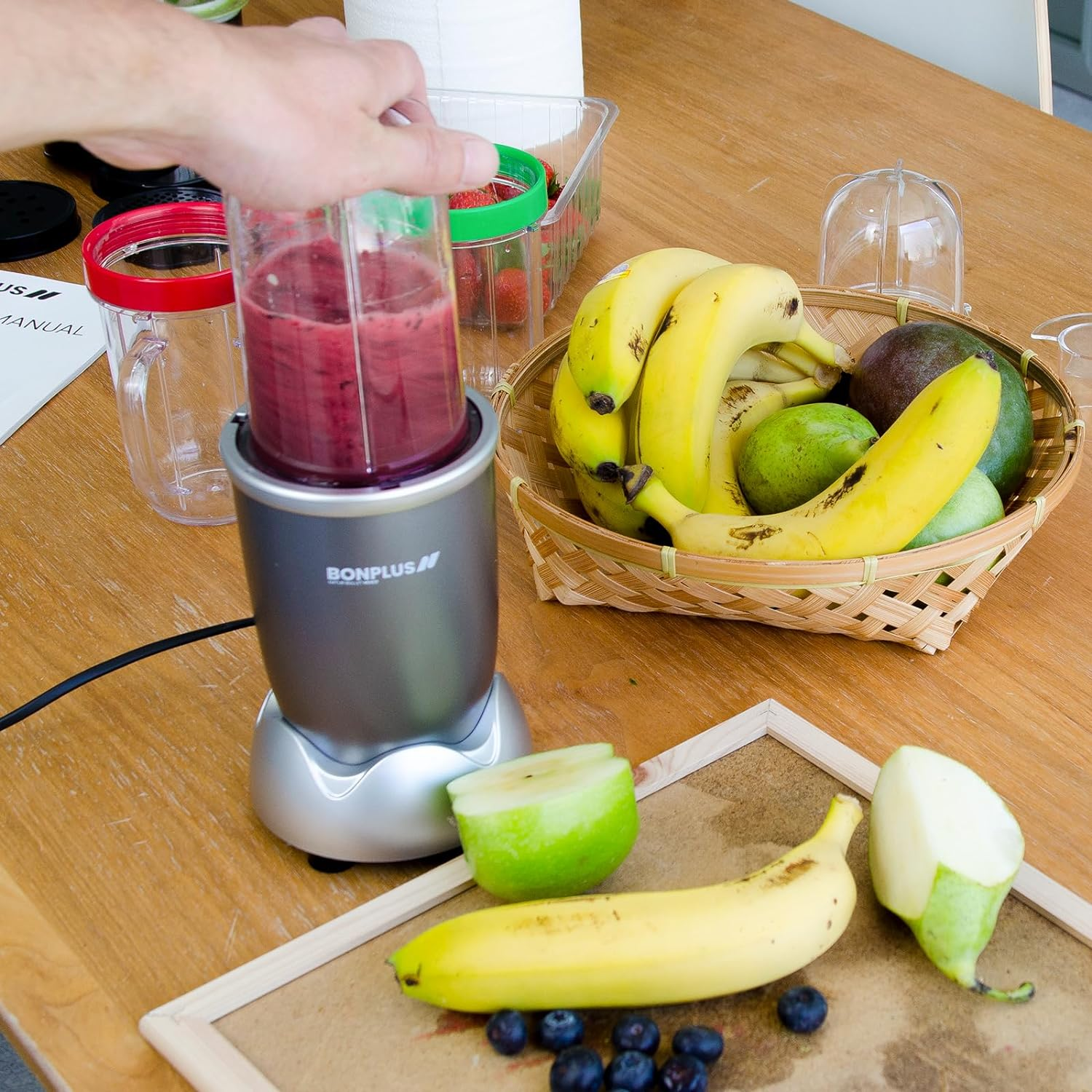 Licuadora con batido, frutas e ingredientes sobre una mesa de madera. Bayas, plátano y manzana.