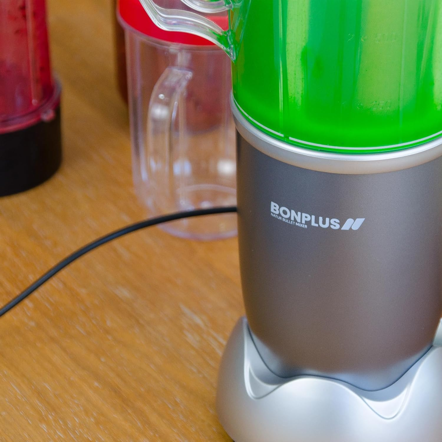 Licuadora con batido verde, logo BONPLUS visible. Fondo de mesa de madera.
