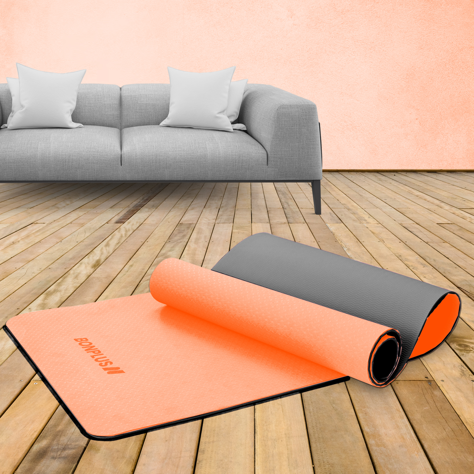 Dos esterillas de yoga, una naranja y otra gris, desplegadas en un suelo de madera, con un sofá al fondo.