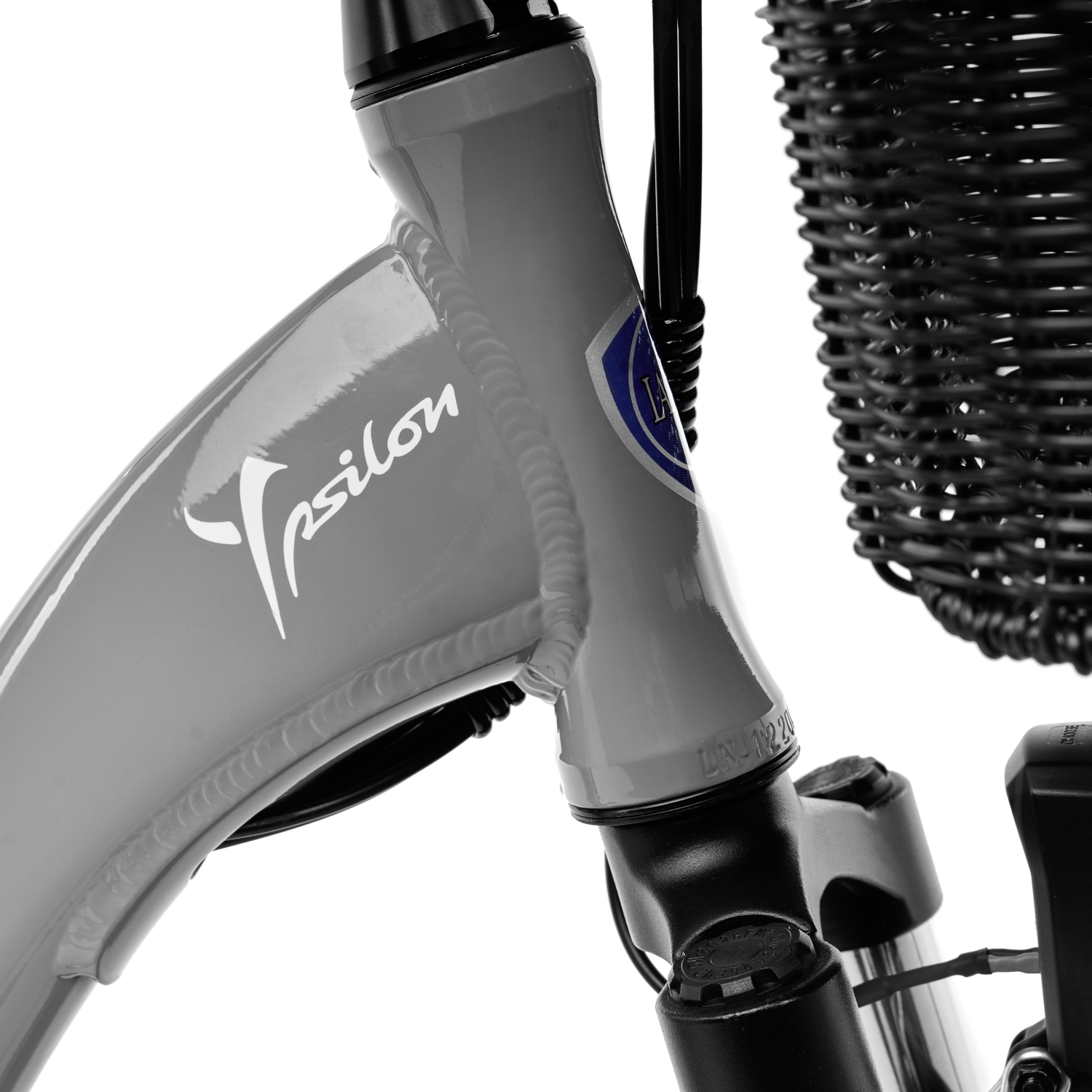 Zbliżenie przedniego widelca szarego roweru z logo 'Tpsilon'.
