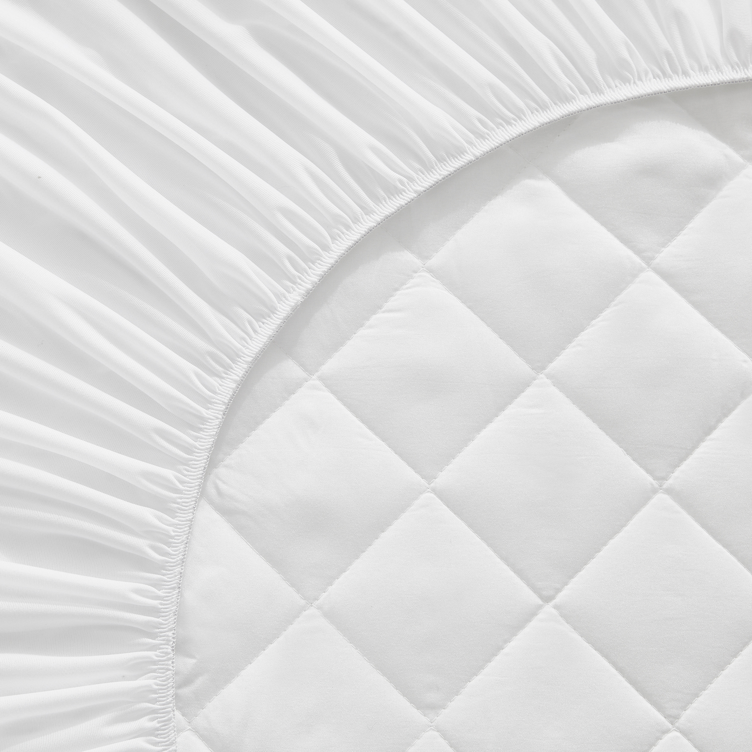Primer plano de una sábana bajera acolchada blanca. Detalles del patrón de acolchado son visibles.