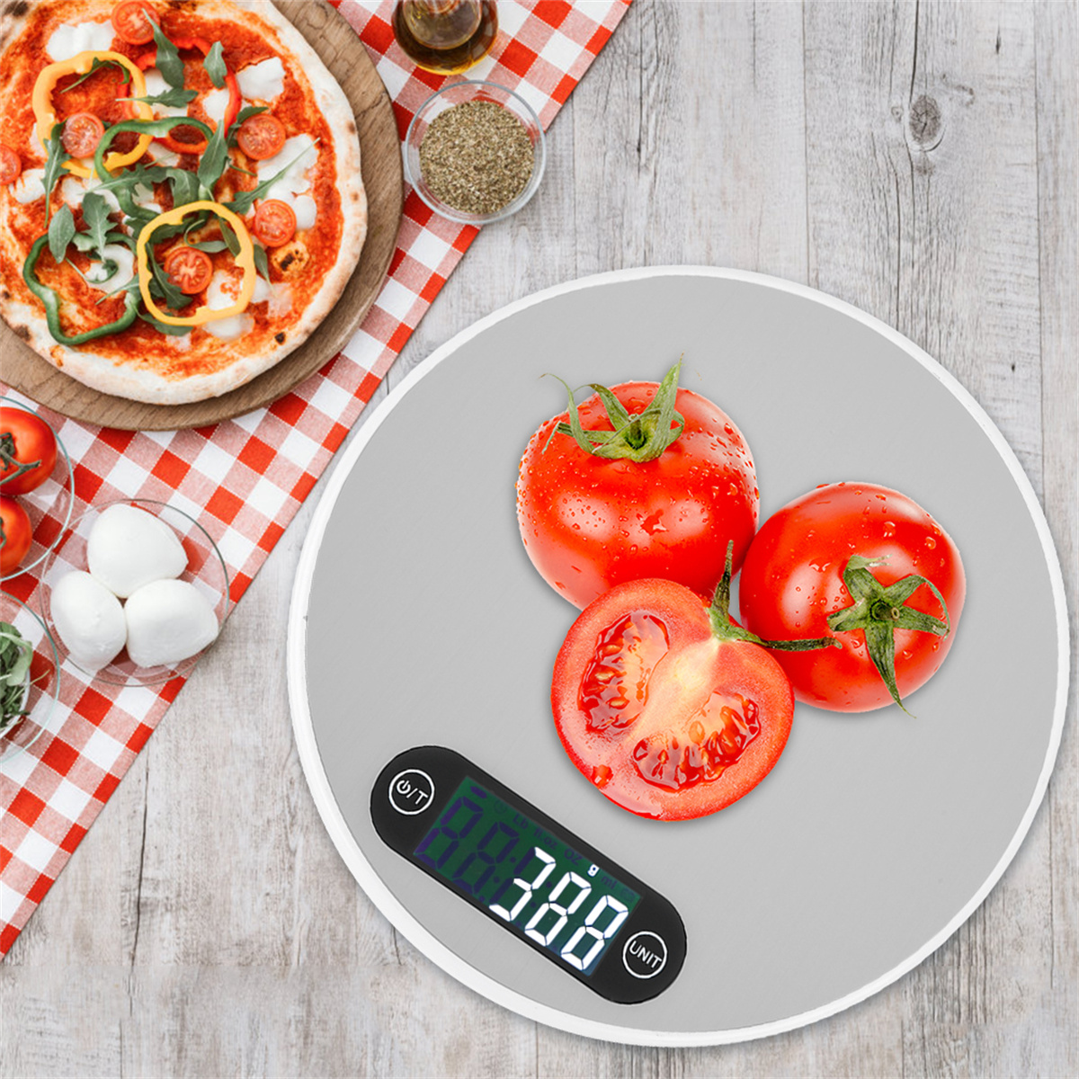 Tomaten auf einer digitalen Küchenwaage mit Pizza im Hintergrund, auf einem Holztisch.