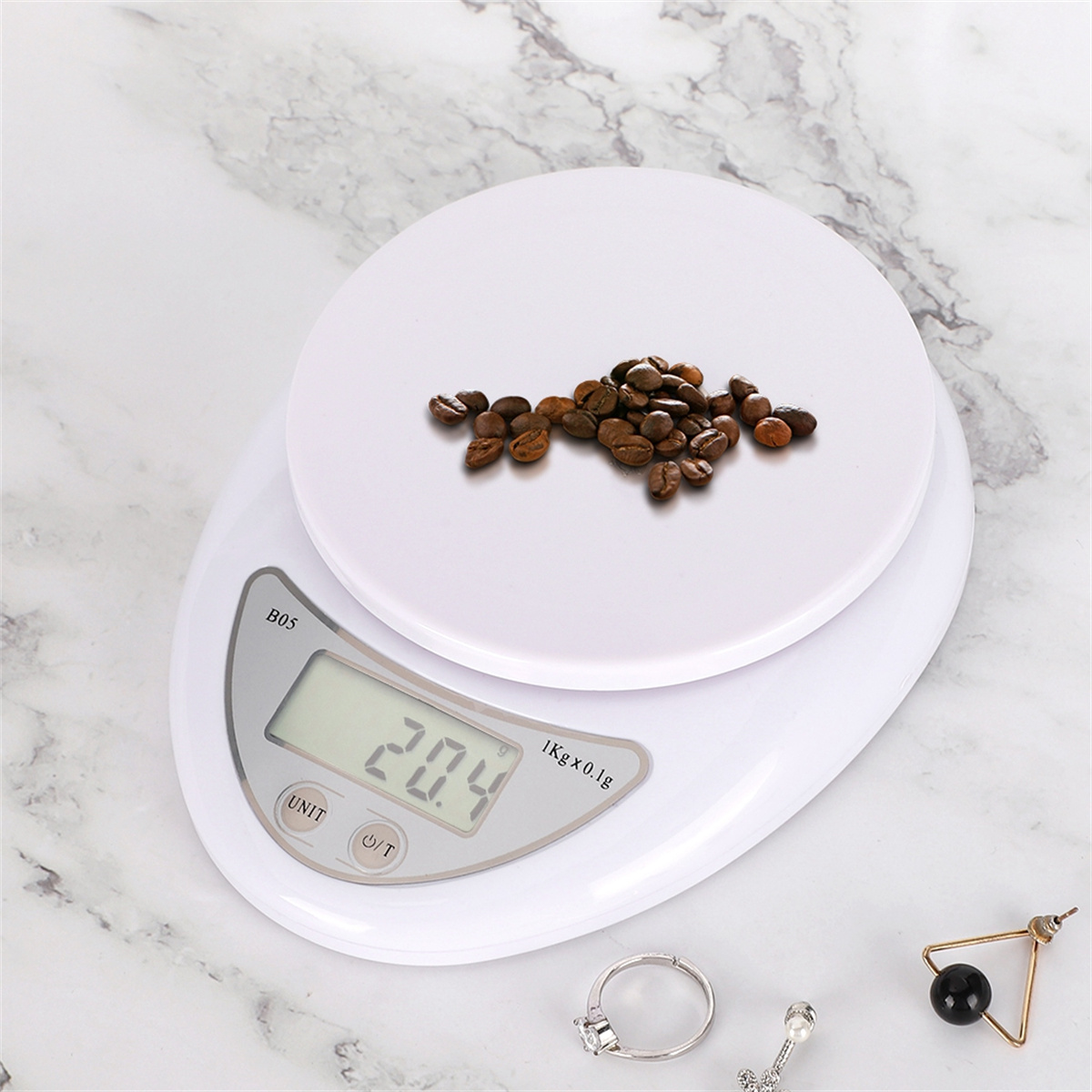 Eine weiße Küchenwaage mit Kaffeebohnen darauf. Ein digitales Display zeigt das Gewicht an.