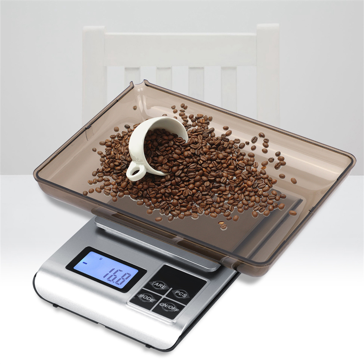 Eine Waage mit Kaffeebohnen in einem Tablett, mit einer weißen Tasse. Ein Stuhl im Hintergrund.