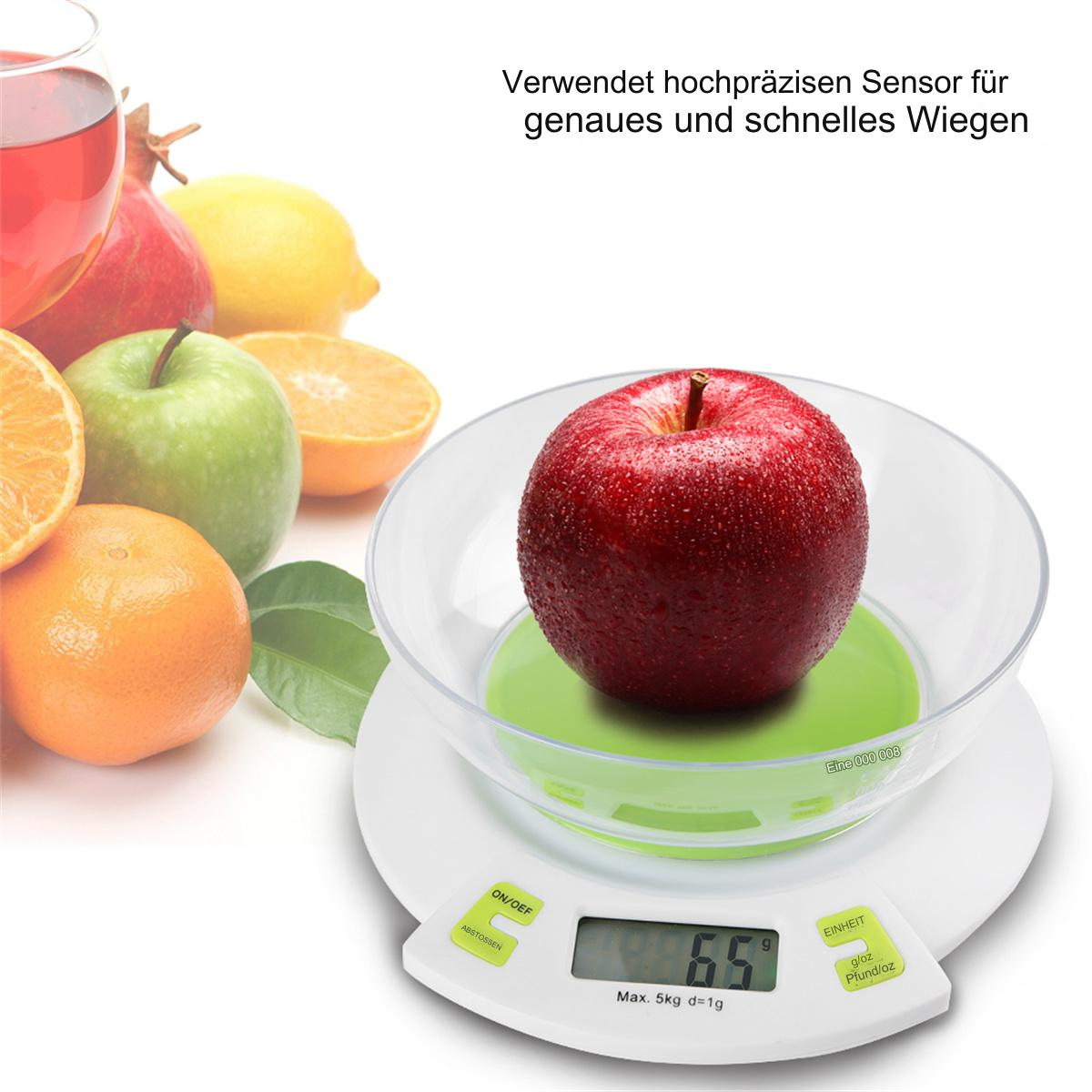 Apfel auf einer Küchenwaage. Grüne Oberfläche, Digitalanzeige zeigt Gewicht. Früchte und Glasschale sichtbar.