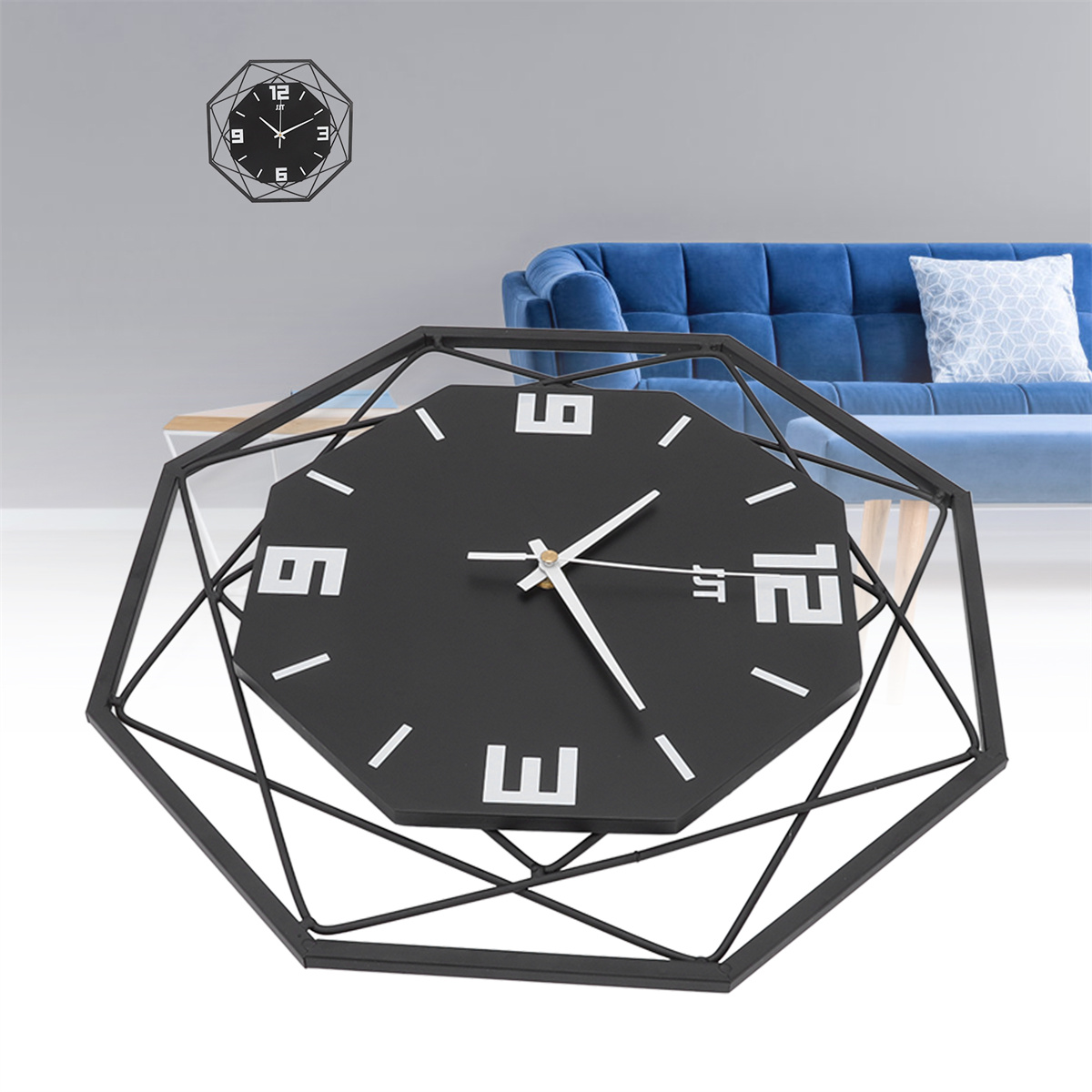 Eine schwarze geometrische Uhr an einer hellgrauen Wand, eine blaue Couch im Hintergrund.