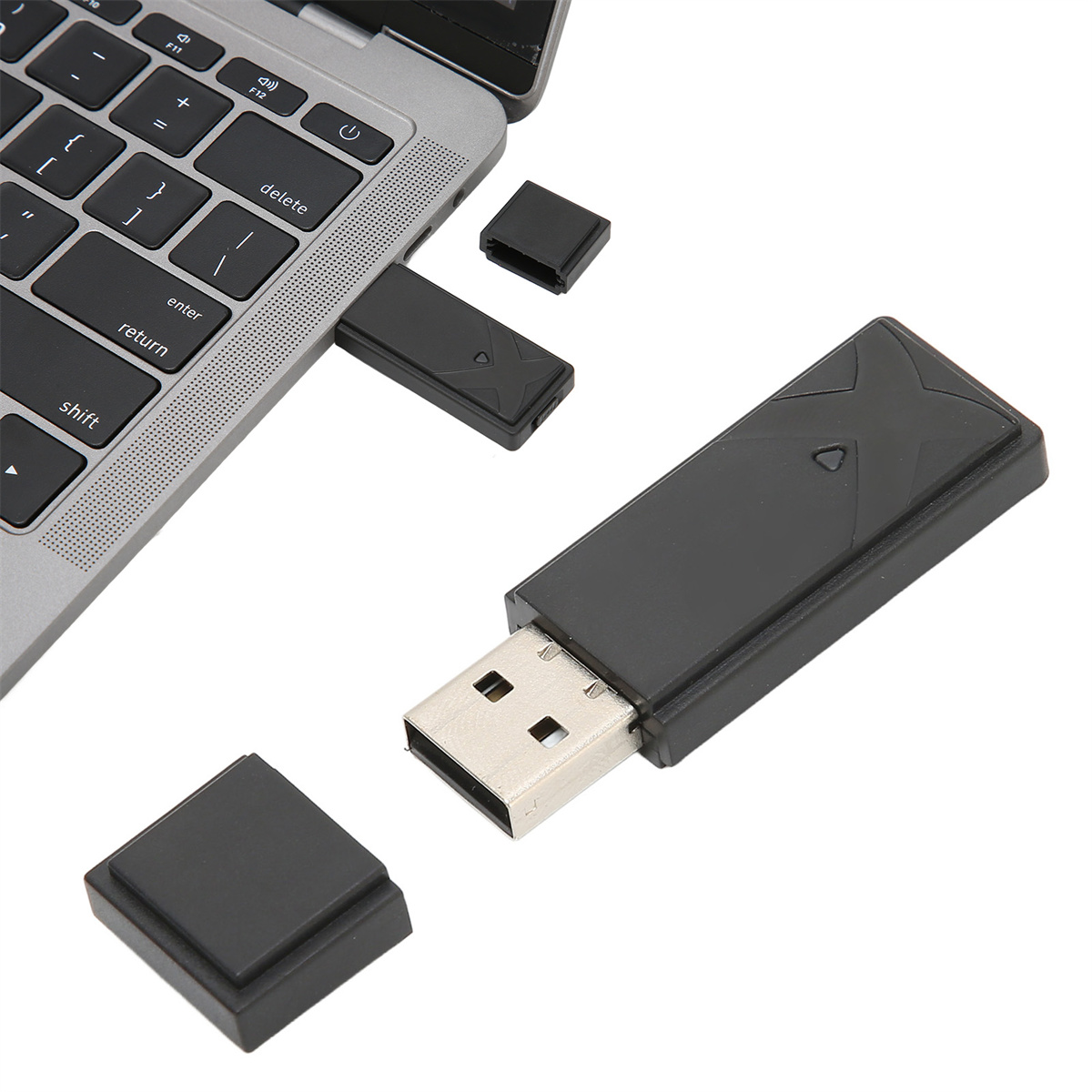 Ein schwarzer USB-Adapter mit Kappen, an einen Laptop angeschlossen. Der Adapter befindet sich neben einer abgezogenen Kappe.