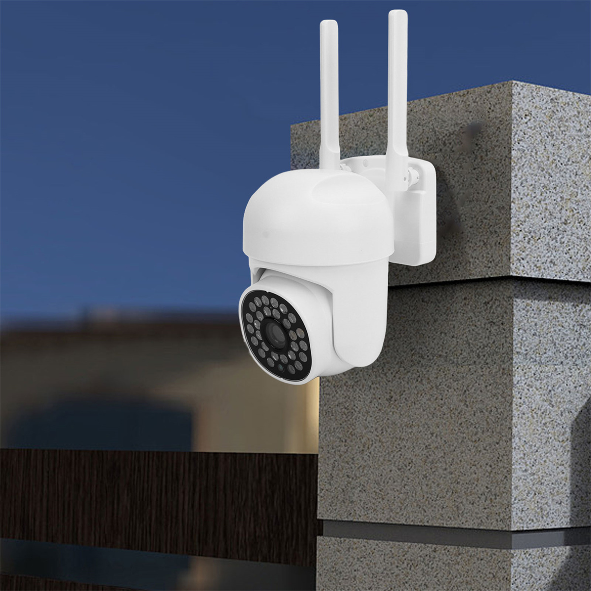 Eine weiße Überwachungskamera an einer Betonmauer mit zwei Antennen vor blauem Himmel.
