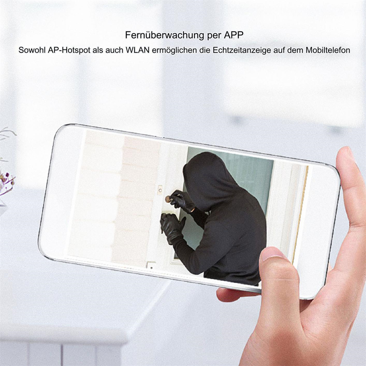 Eine Hand, die ein Telefon hält, das eine Person in einem schwarzen Kapuzenpullover zeigt, die versucht, eine Tür zu öffnen.