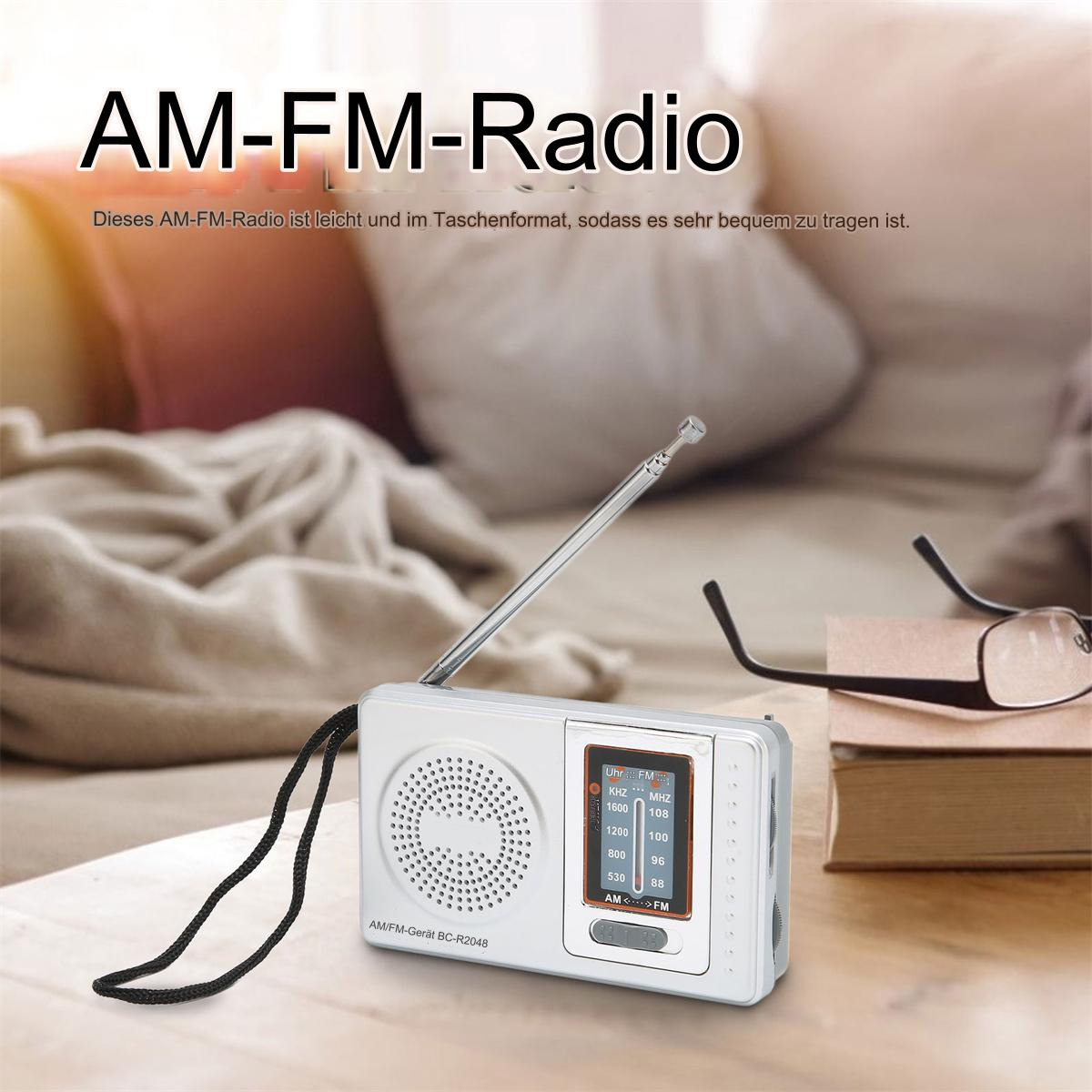 Weißes AM-FM-Radio mit schwarzem Riemen. Ein kleiner Bildschirm zeigt Frequenzen. Text: AM-FM-Radio.