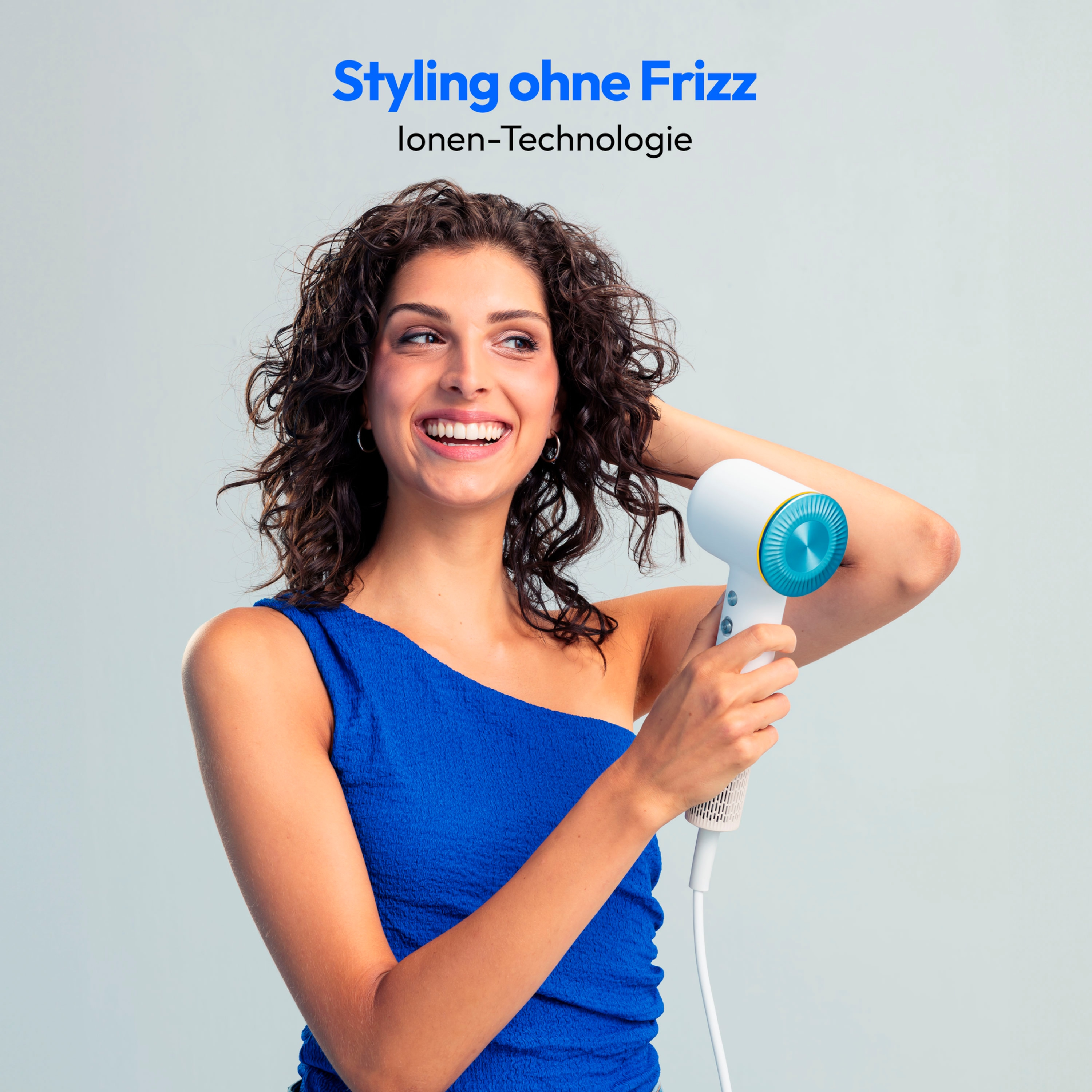 Uśmiechnięta kobieta trzymająca białą i turkusową suszarkę do włosów. Tekst 'Styling ohne Frizz' na górze.