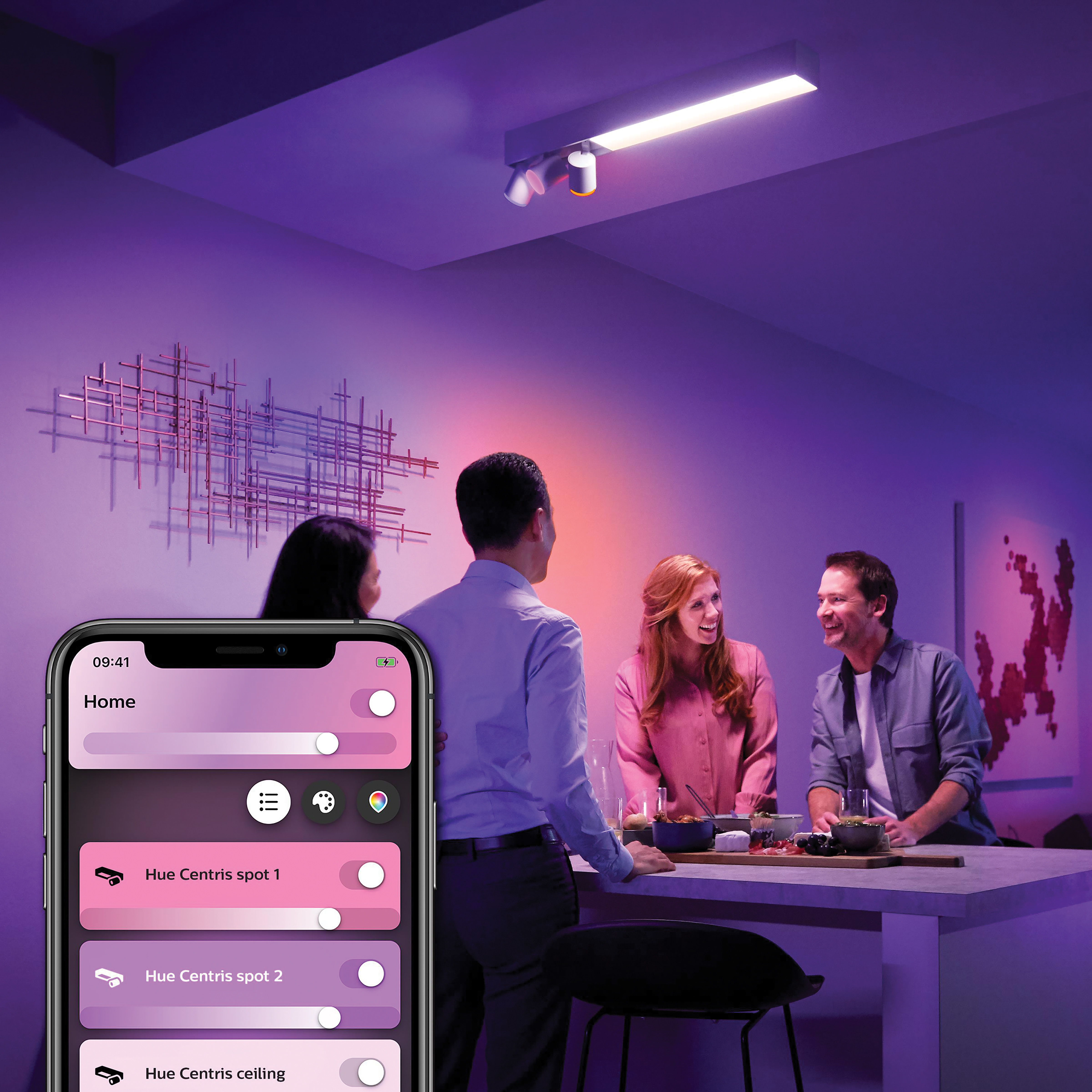 Mensen in een kamer met slimme verlichting, bestuurd door een app op een telefoon.