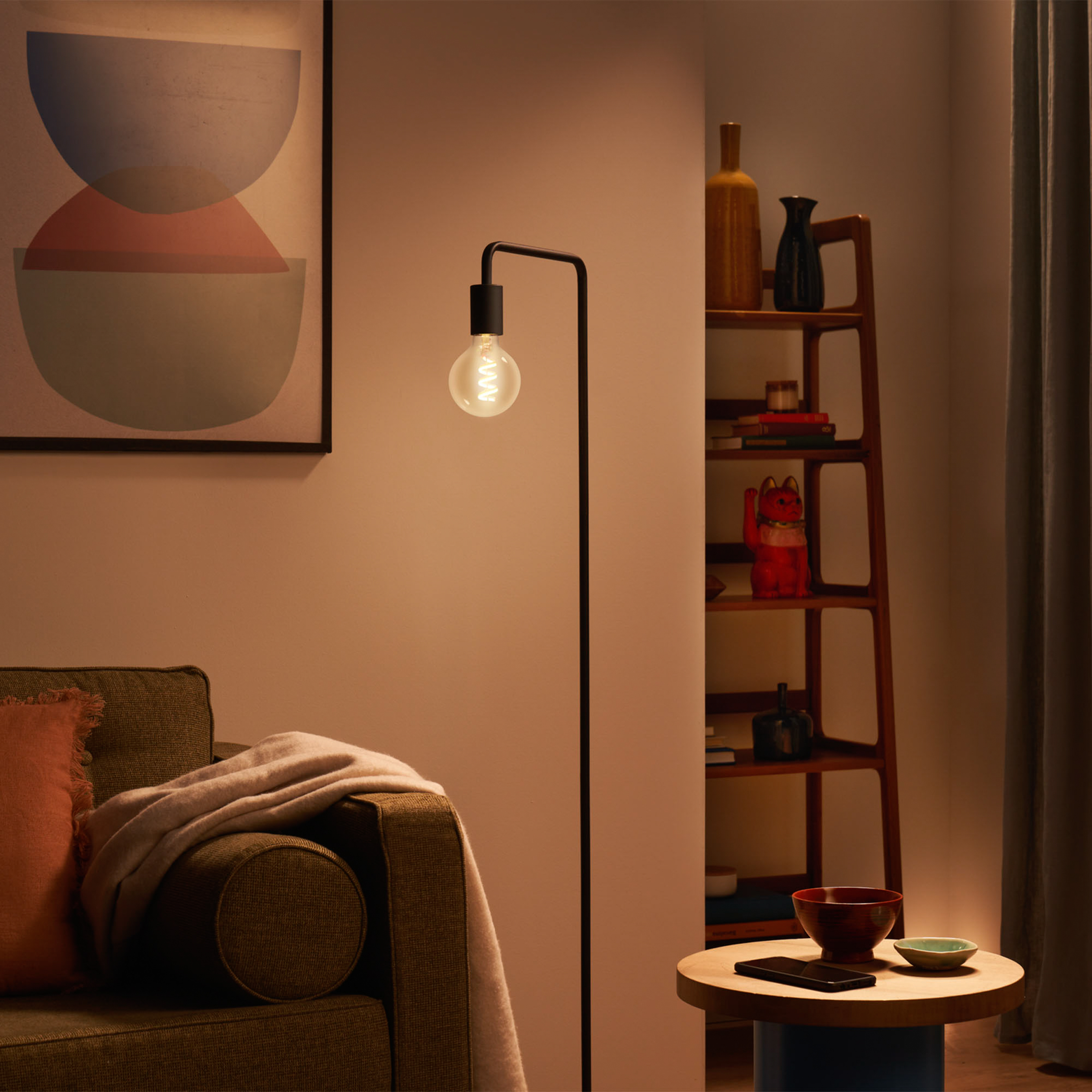 Floor lamp with light, sofa, table, and shelf in background.