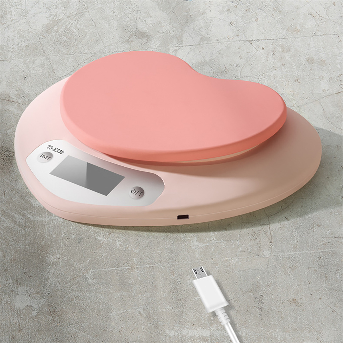 Rosa herzförmige Digitalwaage, mit Ladekabel auf dem Boden.
