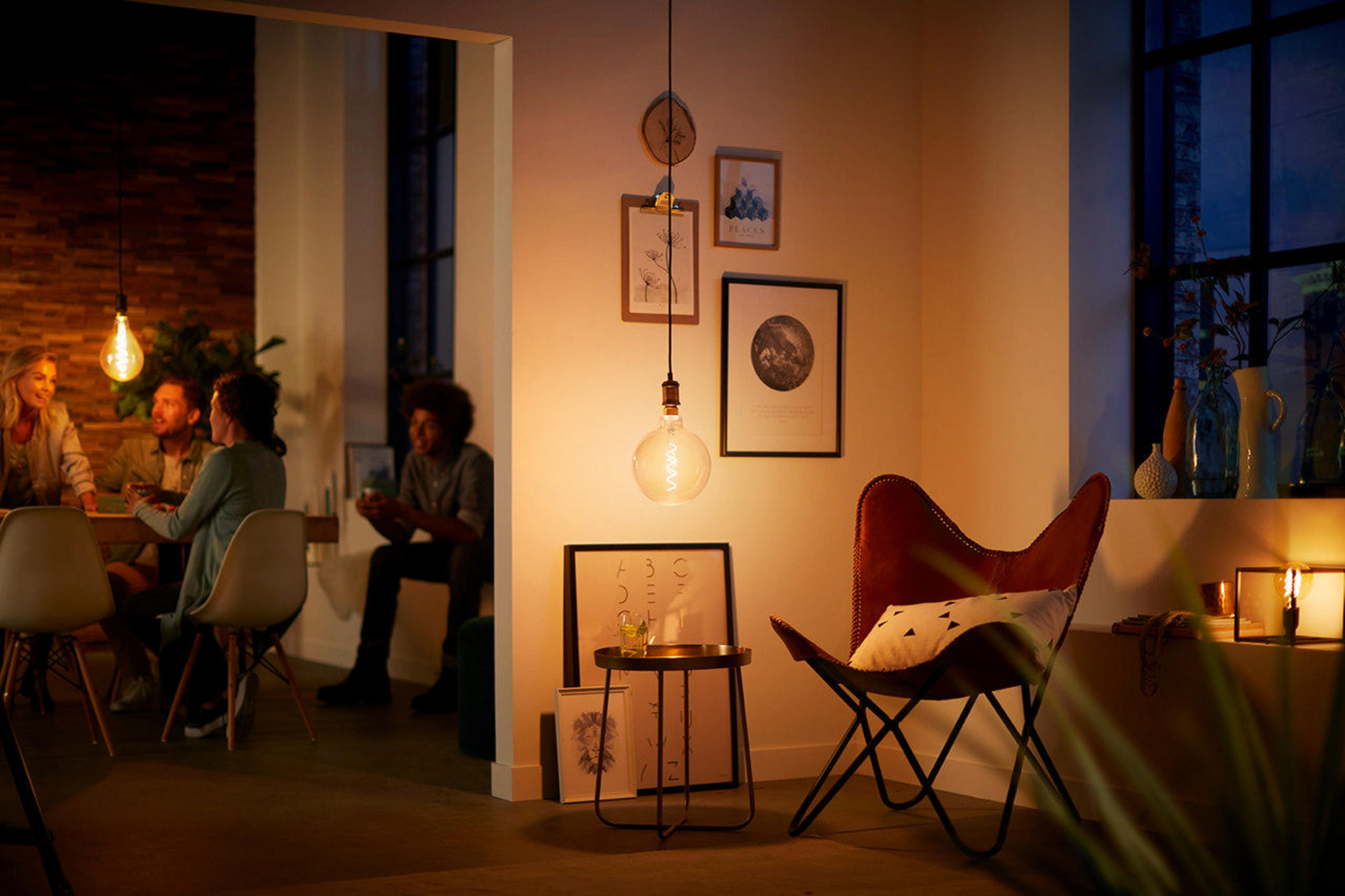 Een woonkamer met mensen, verlicht door hanglampen, creëert een warme sfeer.