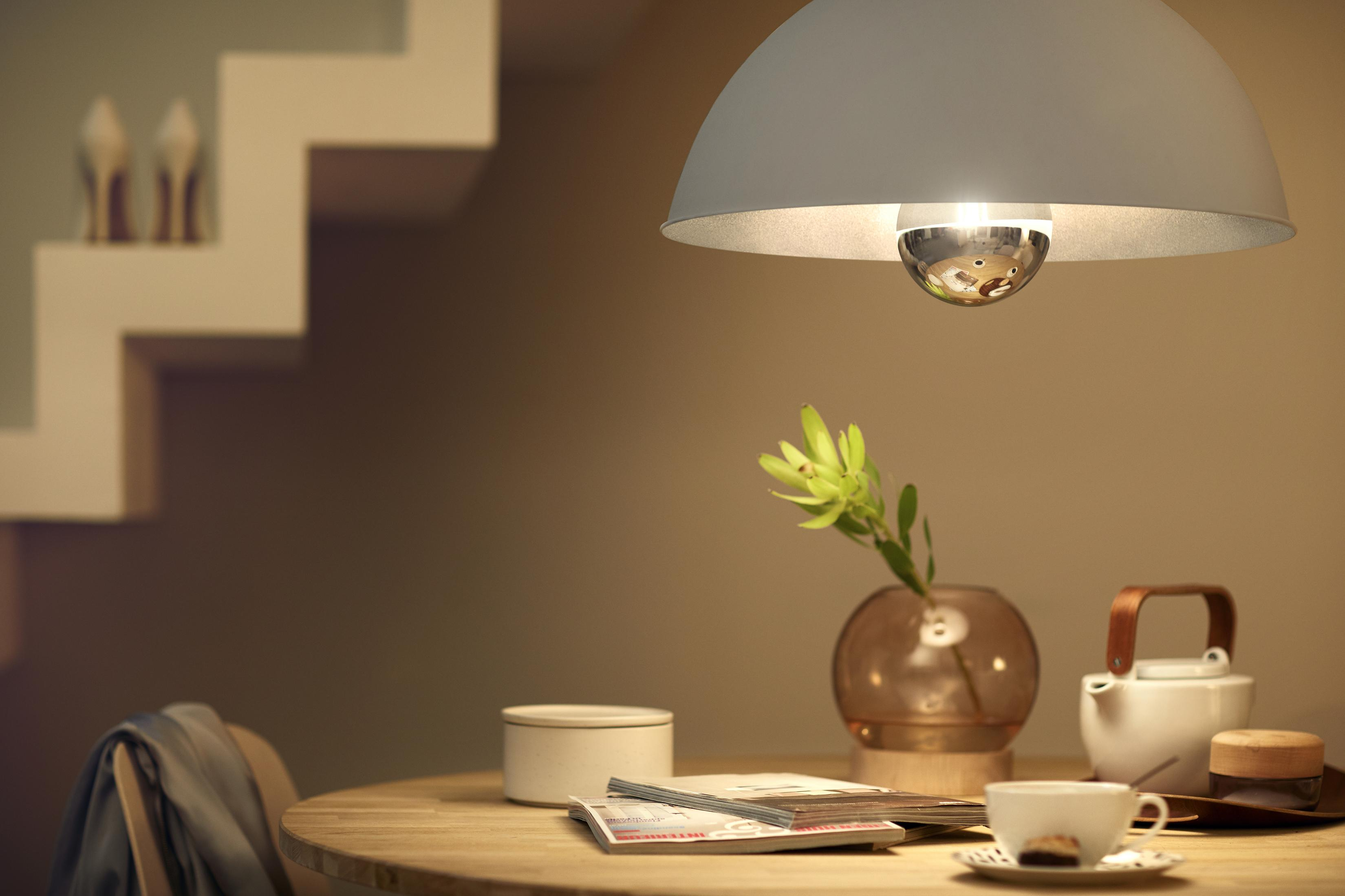 Esstisch mit Lampe, Vase, Teeservice und Zeitschriften. Treppe und High Heels sind im Hintergrund.