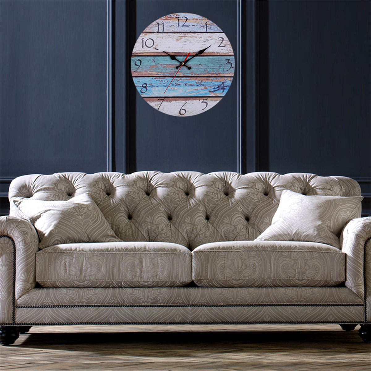 Eine hölzerne Wanduhr mit einem blau-weiß-braunen Zifferblatt über einem beigen Sofa.