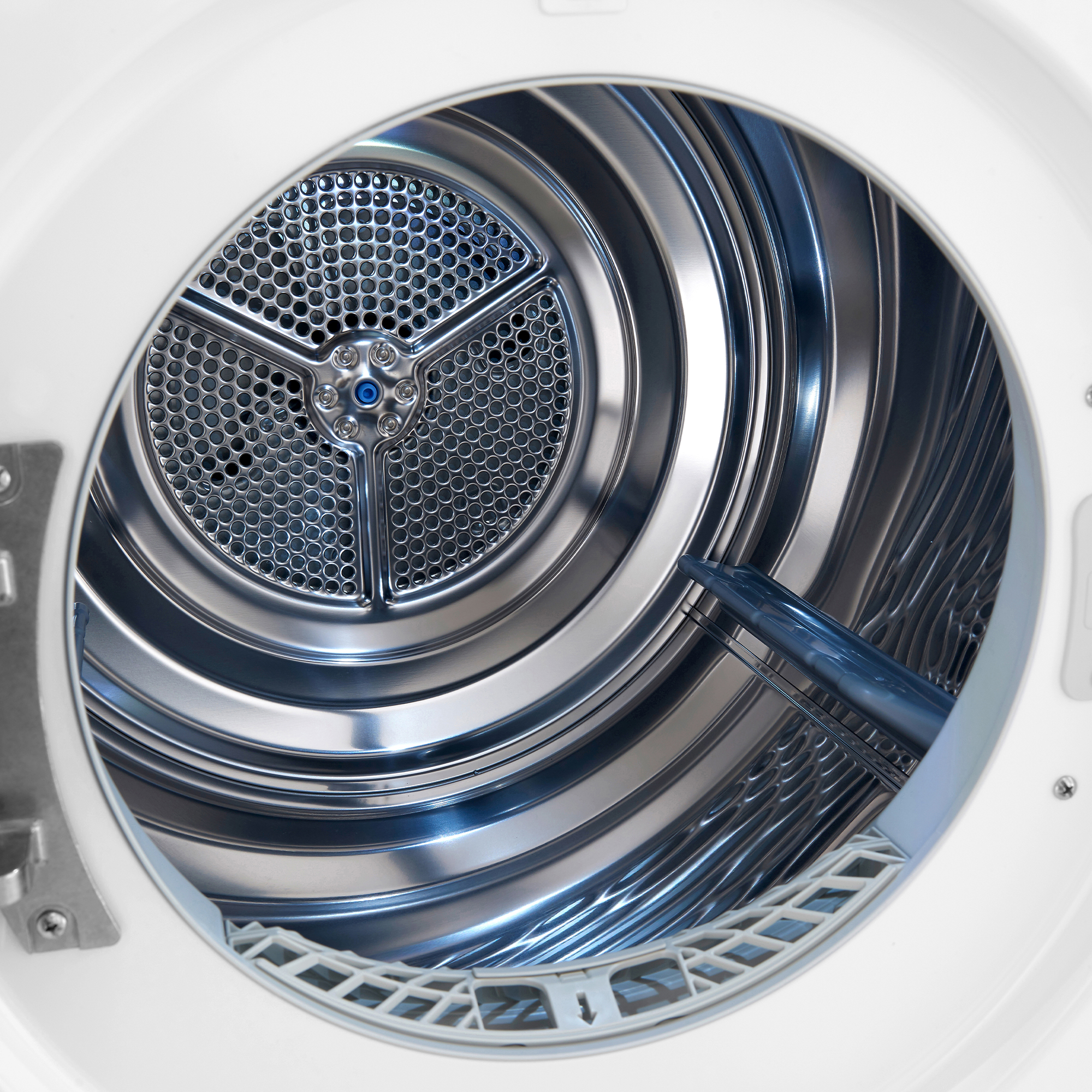 À l'intérieur d'un sèche-linge, un tambour en métal perforé est visible, entouré d'un intérieur métallique brillant.