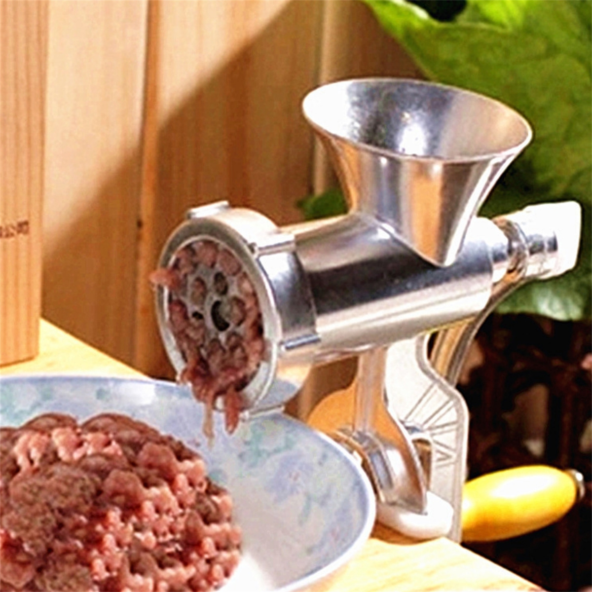 Fleischwolf mit Hackfleisch in einer Schüssel und Holzgrund.