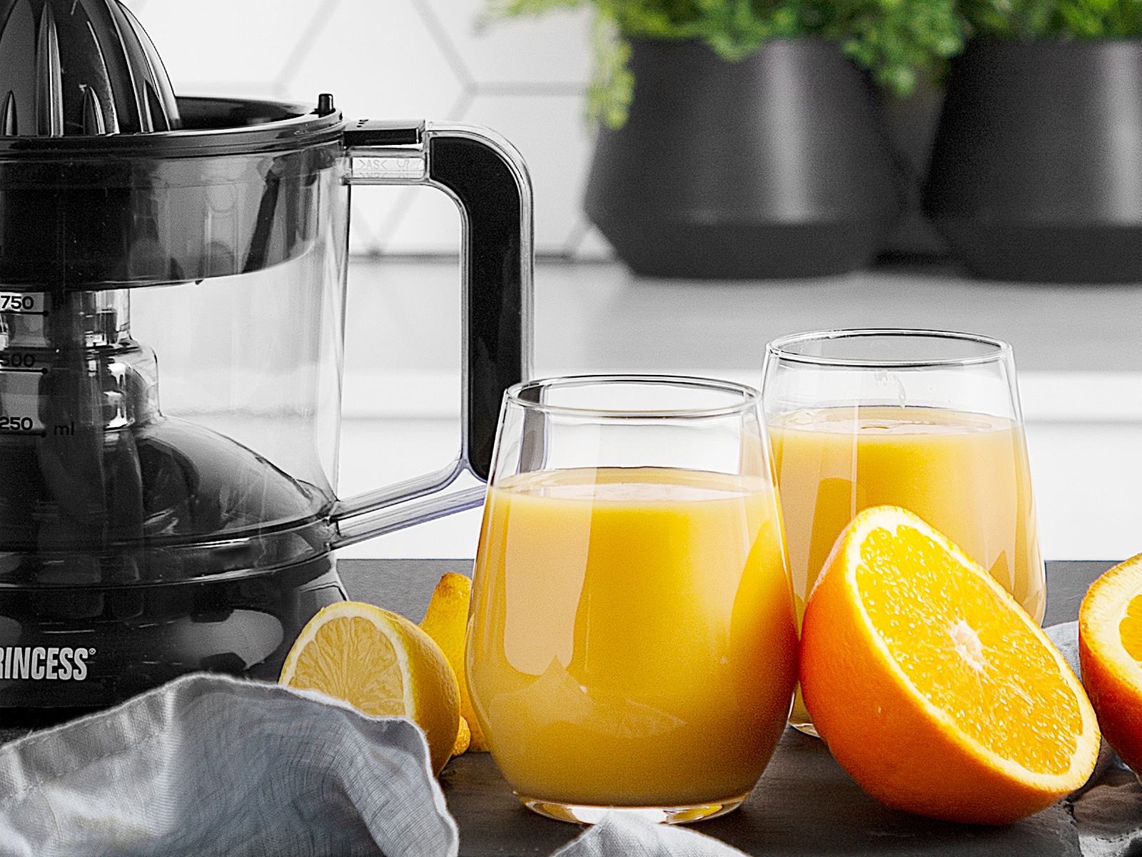 Szklanki soku z sokiem pomarańczowym i wyciskarką na stole.