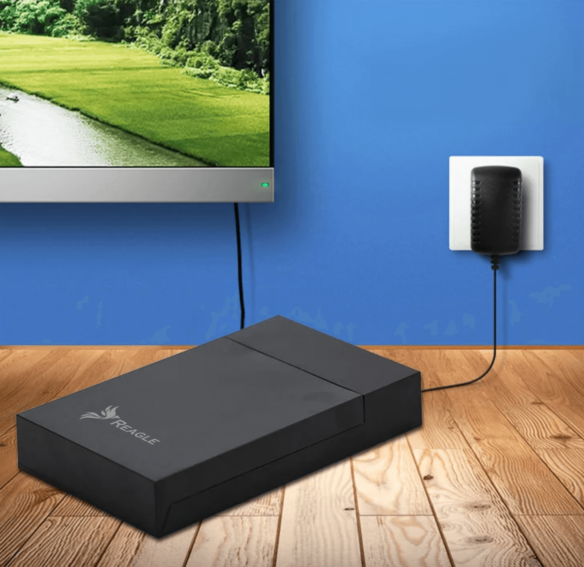 Czarne urządzenie i zasilacz w pobliżu telewizora, podłączone do niebieskiej ściany z drewnianą podłogą.