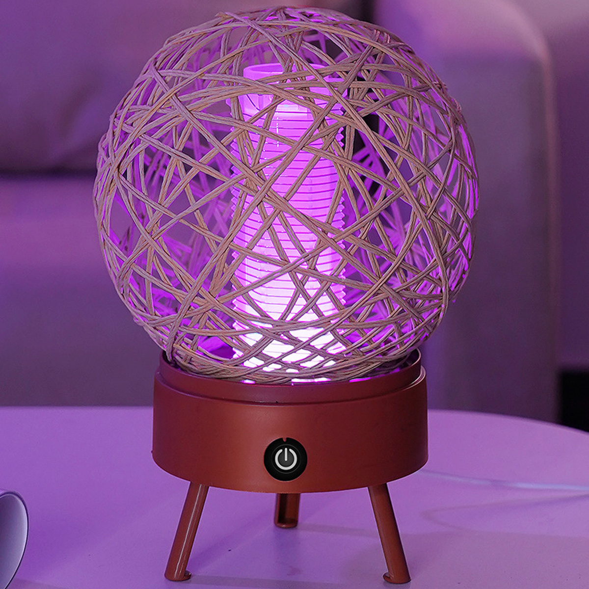 Runde Lampe mit Weidenholz-Außen und lila Innenbeleuchtung. Auf braunem Sockel.