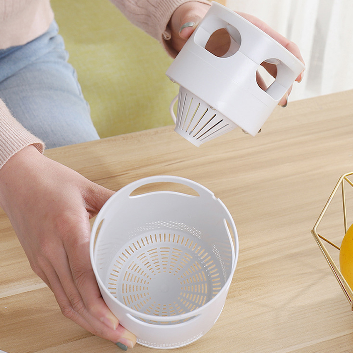 Weißes Küchenutensil mit separatem Korb und Griff. Frau hält es hoch, bereit für den Gebrauch.