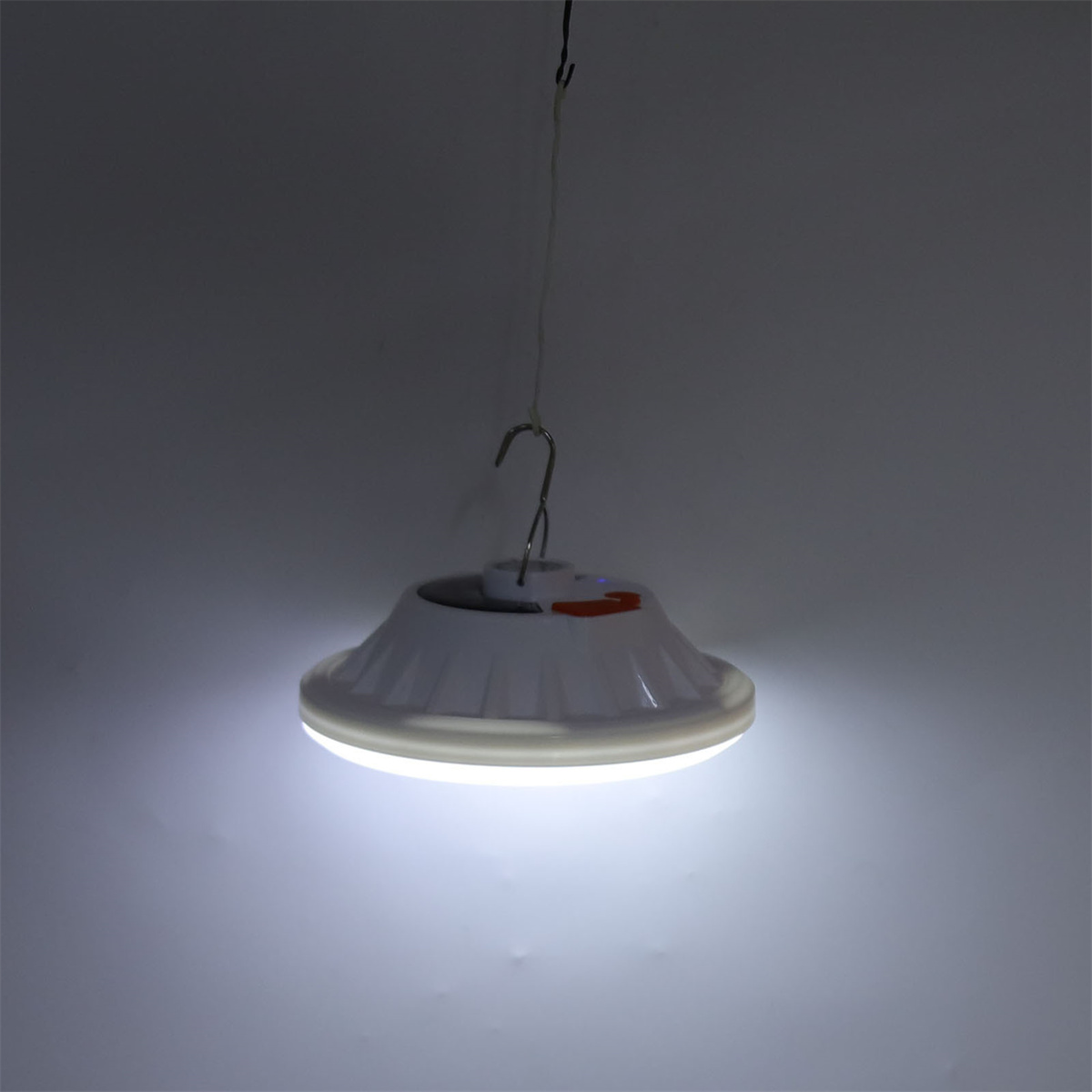 Eine weiße Hängelampe, die Licht aussendet. Sie hat einen Haken und eine kreisförmige Lichtquelle.