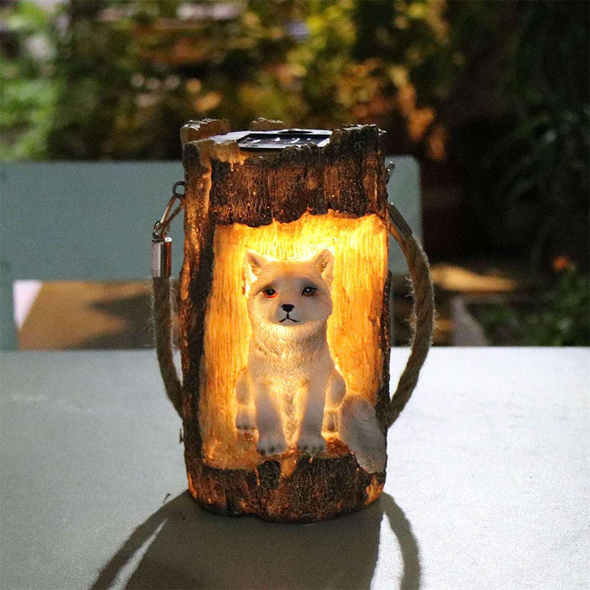 Eine beleuchtete hölzerne Fuchslaterne mit einer weißen Fuchfigur im Inneren, auf einer Oberfläche.