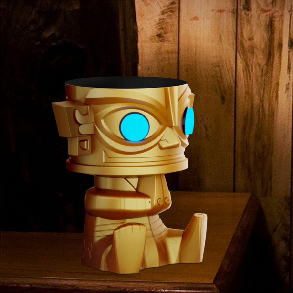 Eine goldfarbene Figur mit blauen Augen wird auf einer Holzoberfläche gezeigt.