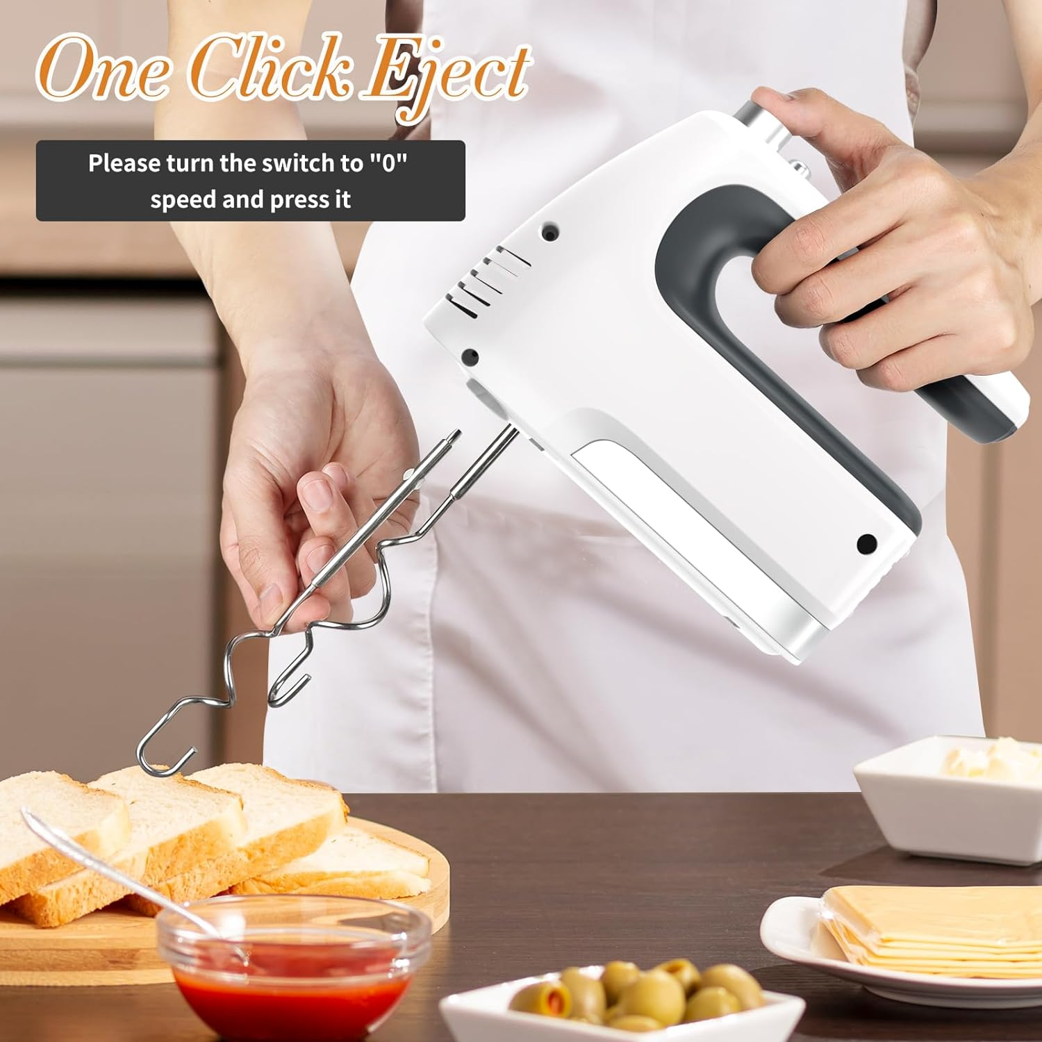 Ein Handmixer mit herausspringenden Klingen. Brot, Soße und Oliven stehen auf dem Tisch. Text: One Click Eject.