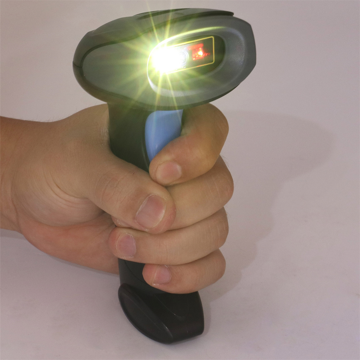 Eine Hand hält einen schwarzen Barcode-Scanner, aus dem rotes Licht austritt.