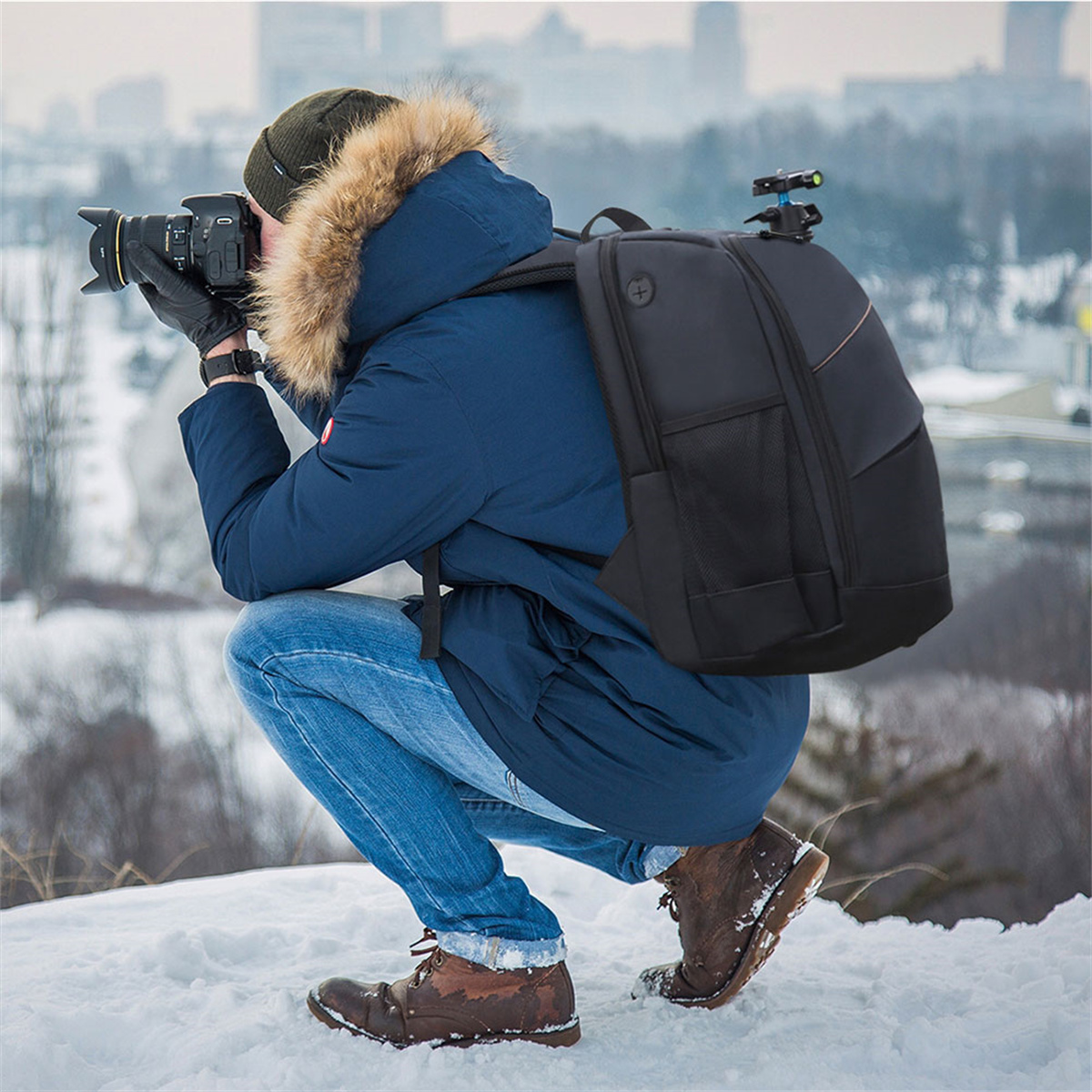 Eine Person macht ein Foto im Schnee. Sie trägt eine blaue Jacke und einen schwarzen Rucksack. Schneeiger Hintergrund.