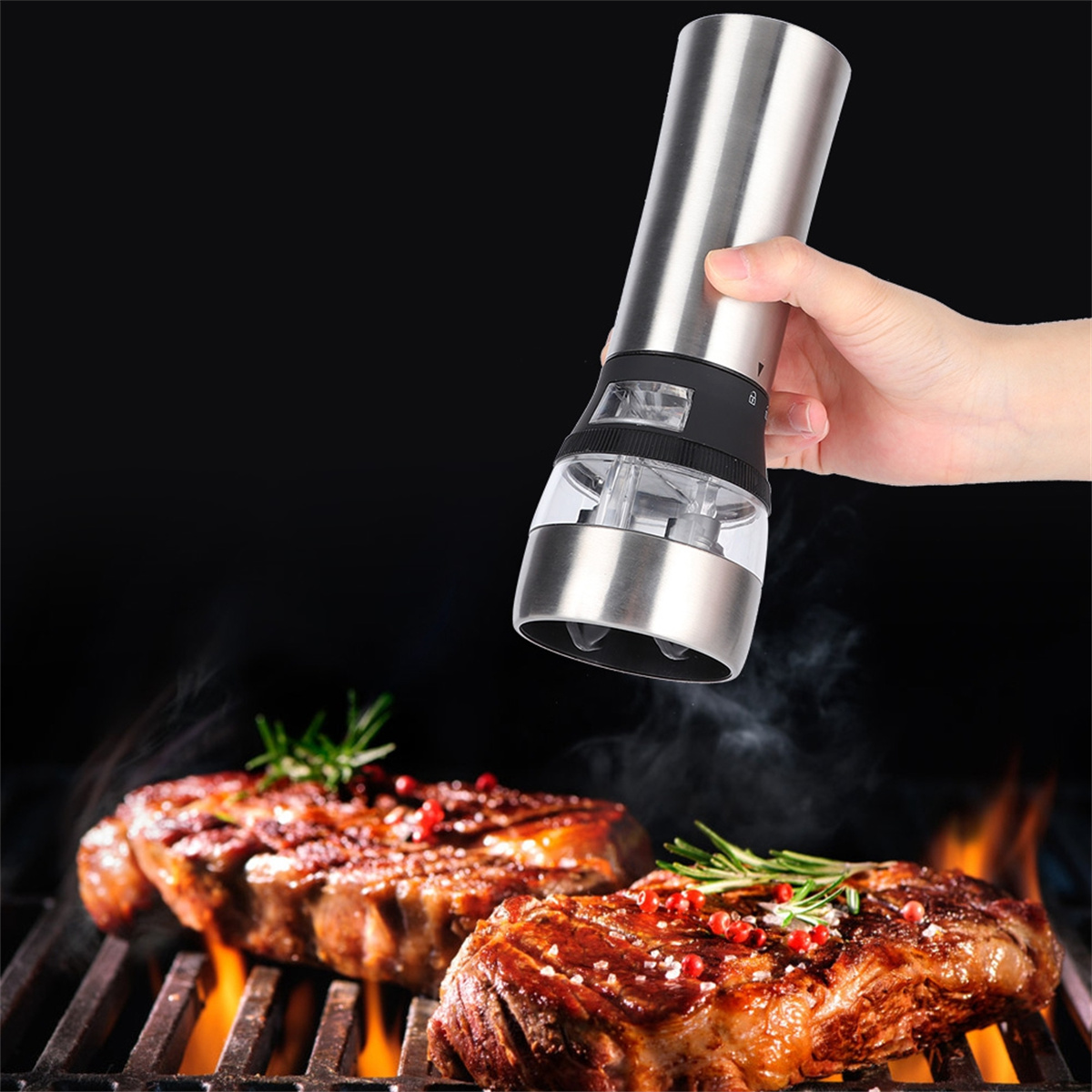 Elektrische Pfeffermühle aus Edelstahl. Steaks auf einem Grill mit Flammen und Rauch. Hand hält Mühle.
