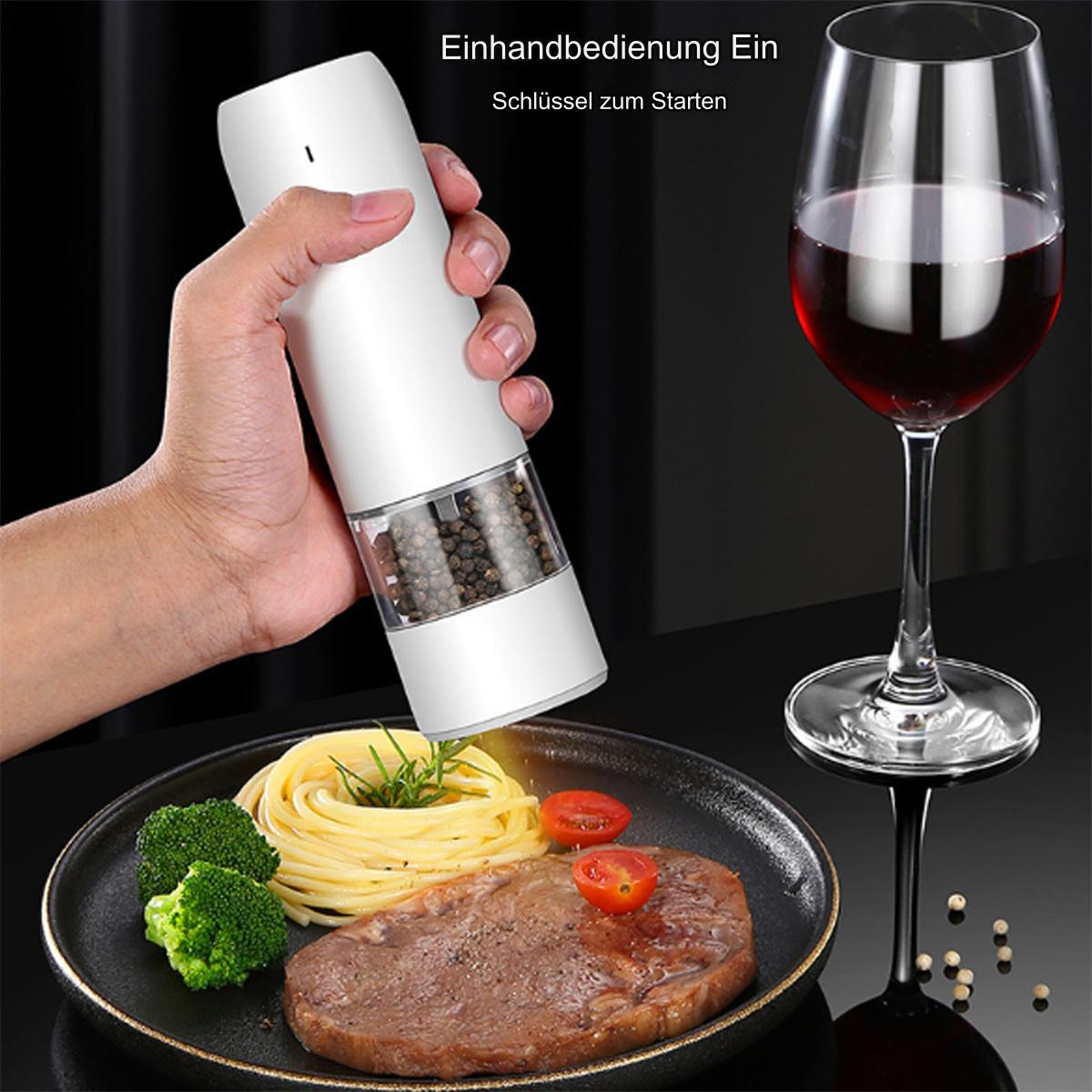 Hand hält eine weiße Pfeffermühle neben einem Teller mit Essen, Weinglas und Rotwein.