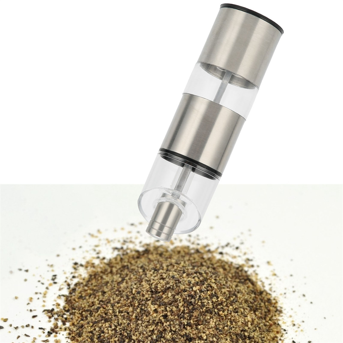 Silber- und transparente Pfeffermühle über einem Haufen gemahlenen Pfeffers.