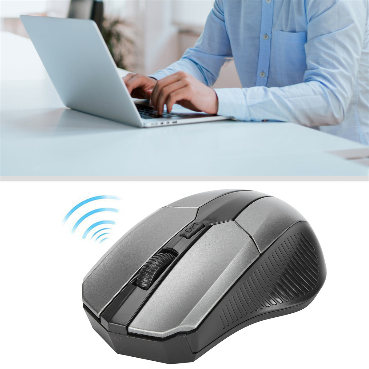 Eine graue und schwarze kabellose Maus neben einer Person, die einen Laptop an einem weißen Schreibtisch benutzt.