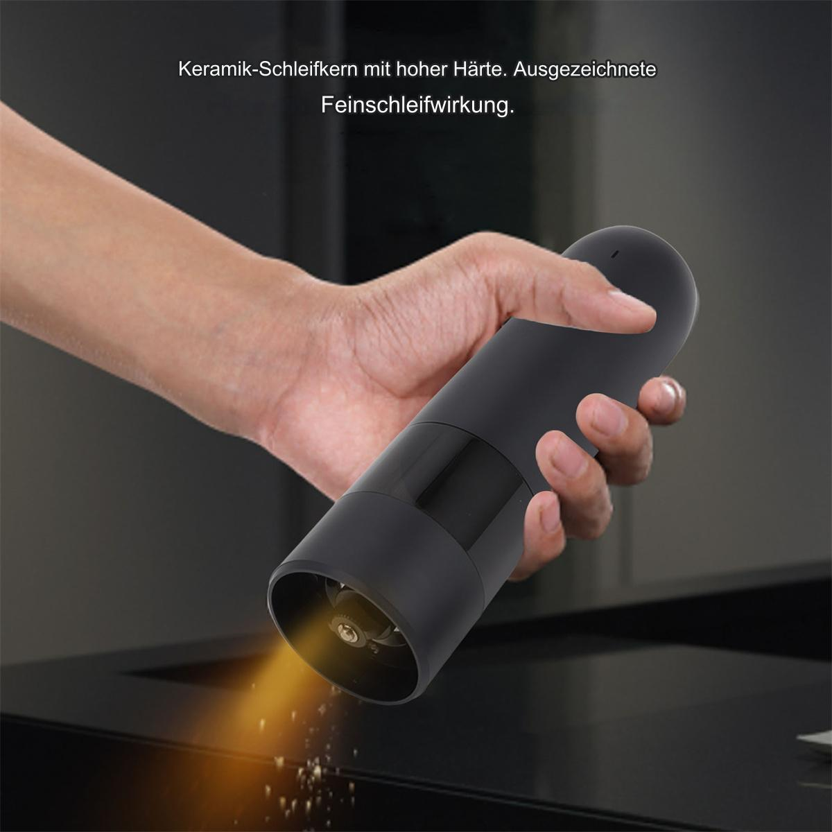 Hand hält eine schwarze Pfeffermühle, zeigt das Mahlen und den Pfeffer.