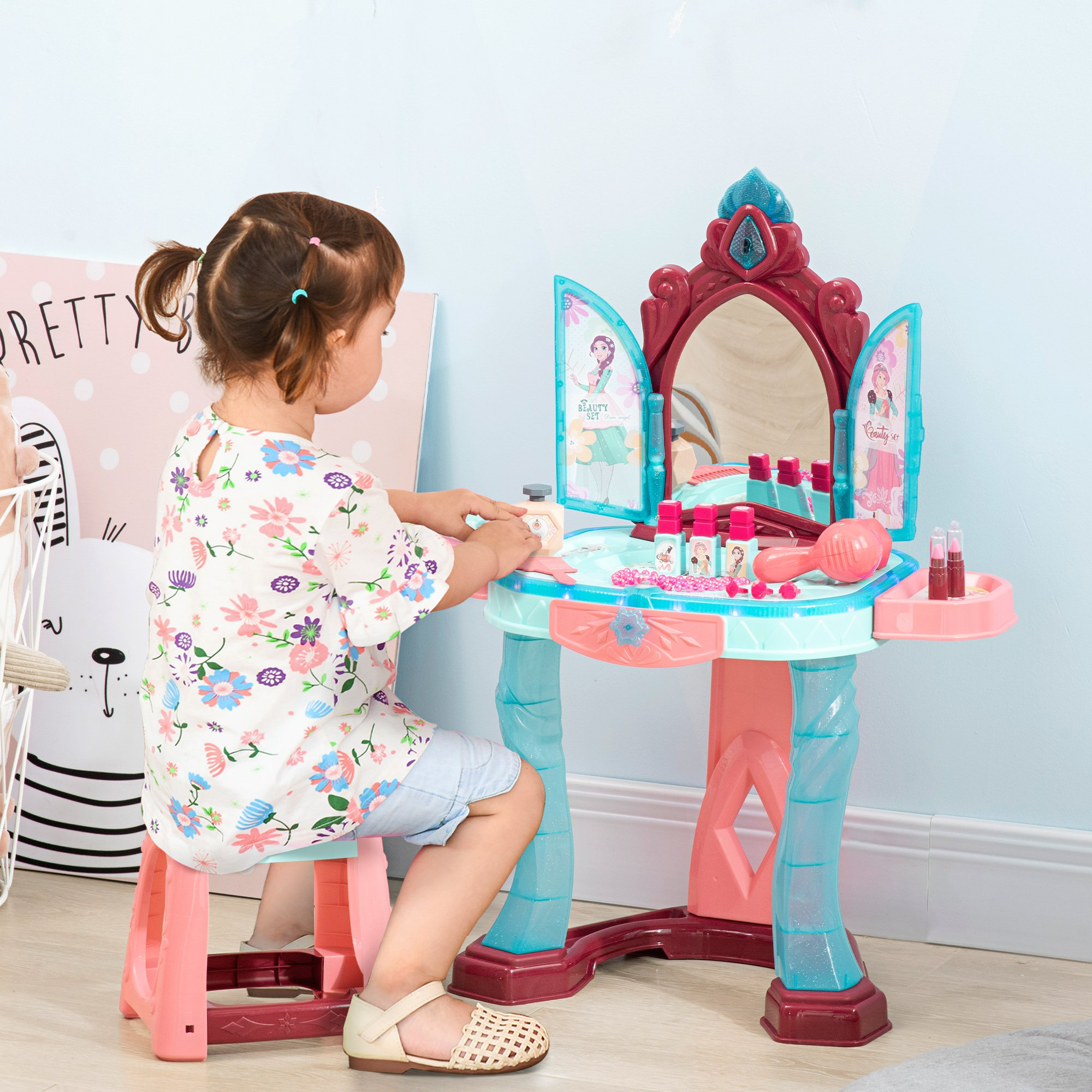 Una niña sentada en una mesa de tocador rosa y azul, jugando con maquillaje.