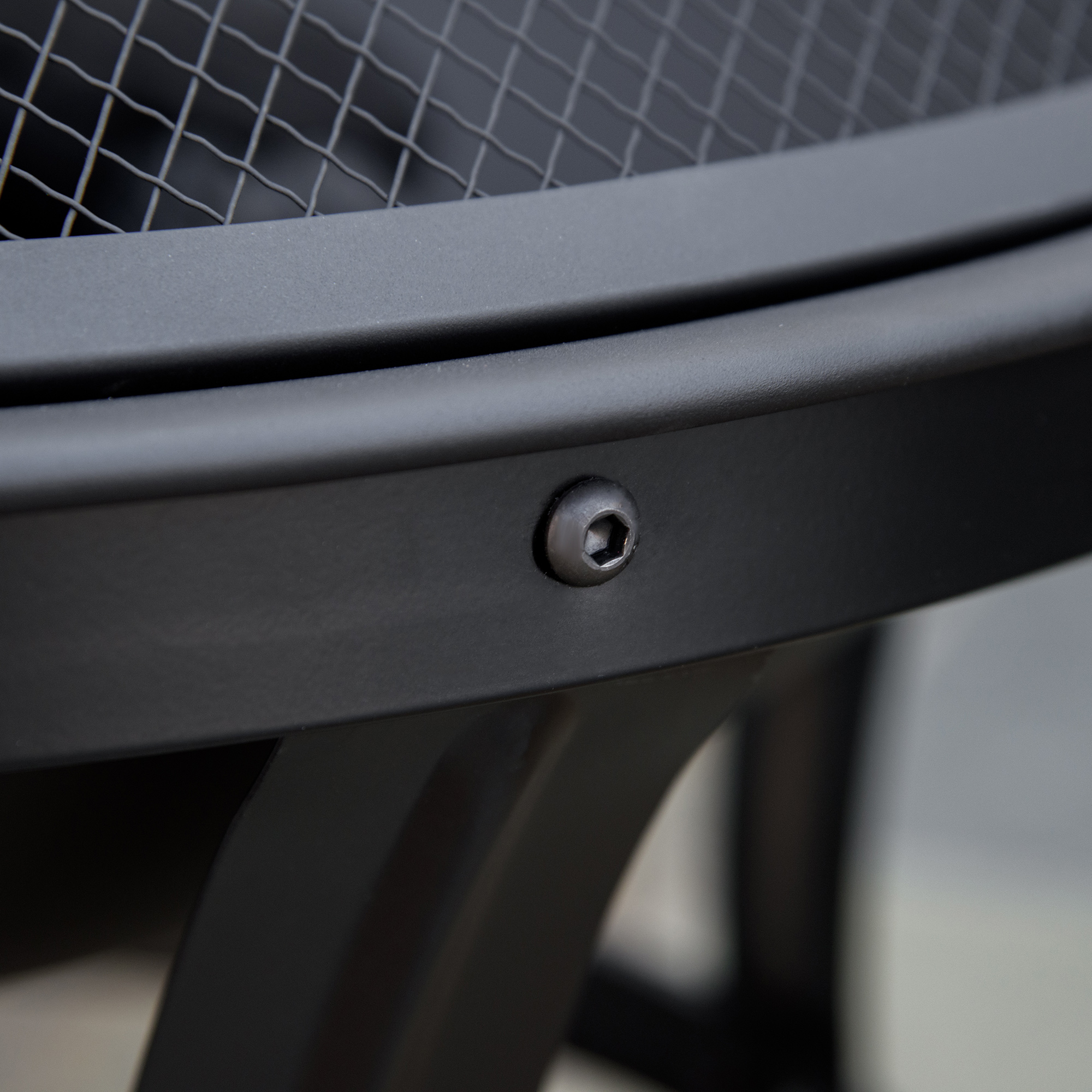 Primer plano de una hoguera de metal negro con una cubierta de malla negra y un perno.