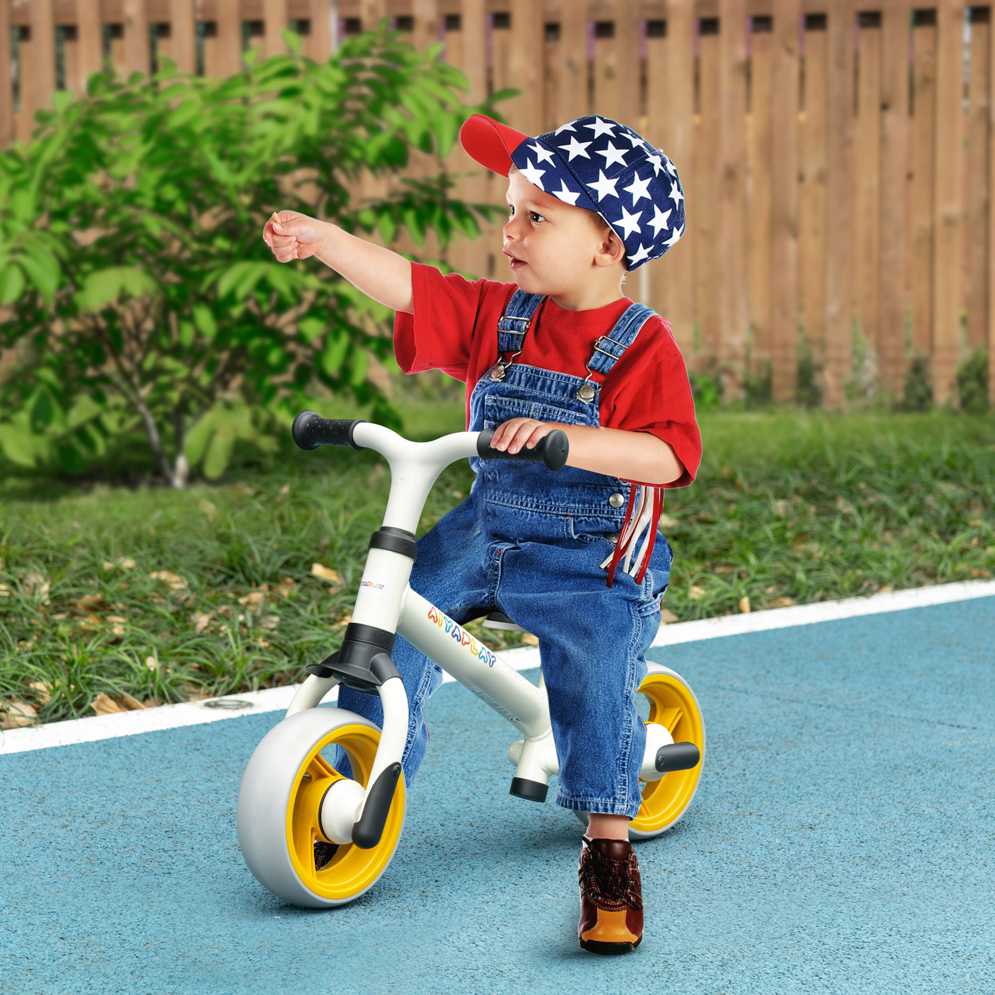 Niño montando en bicicleta de equilibrio en camino azul. El niño señala con la mano derecha.