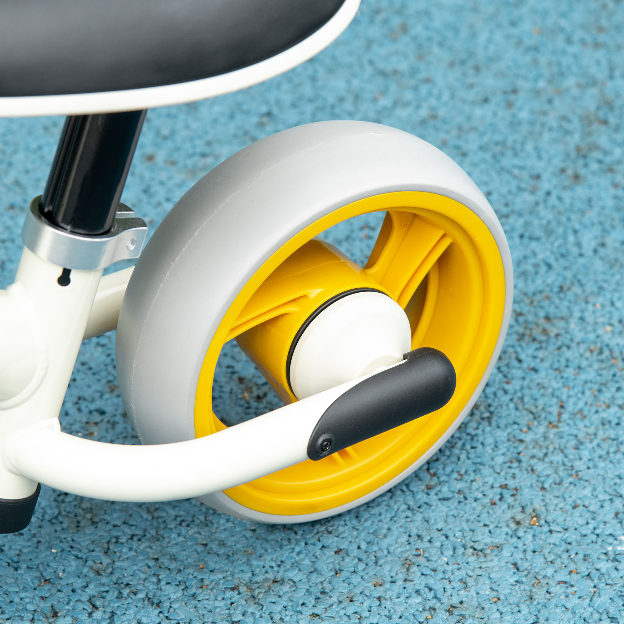 Primer plano de una rueda de triciclo con centro amarillo y neumático gris.