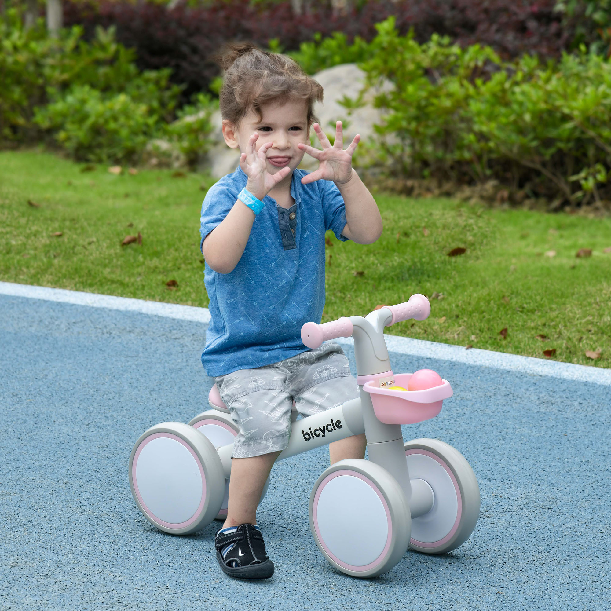 Un niño pequeño montando en bicicleta de equilibrio gris y rosa.
